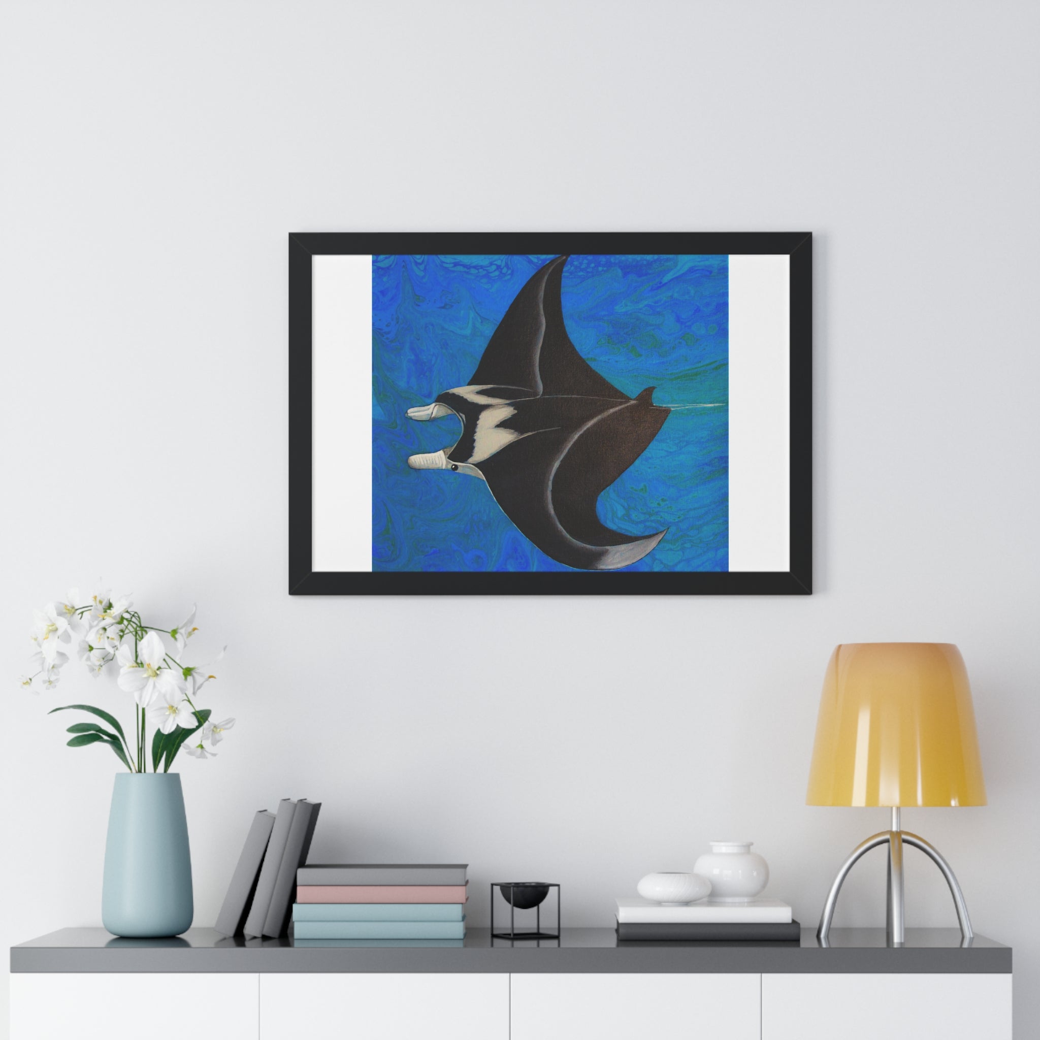 Framed artwork of a manta ray on a wall above a shelf with decor items.