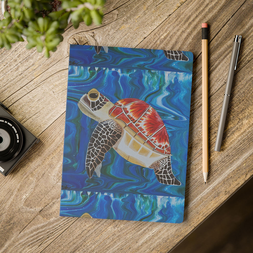 Notebook with a turtle design on a wooden surface with stationery items.