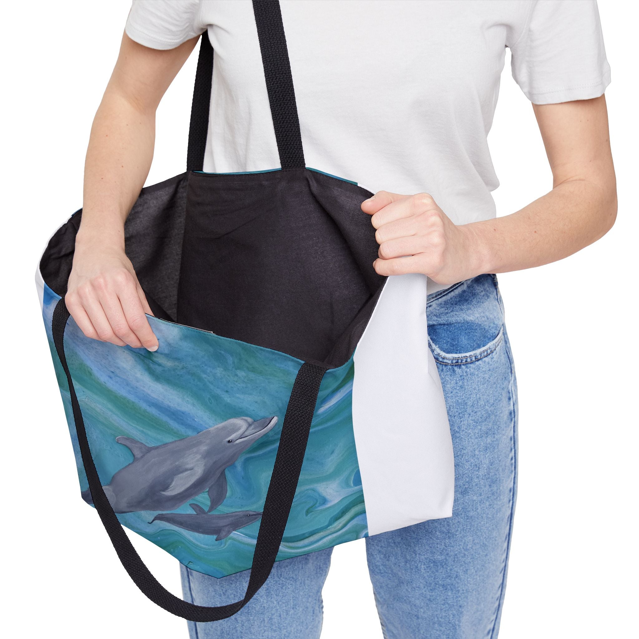 Person holding a tote bag with dolphin design on a white background