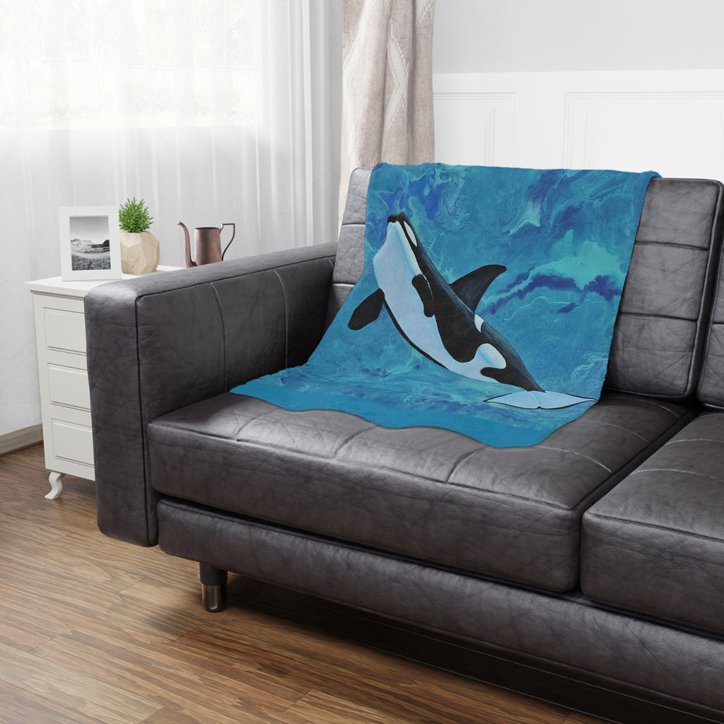 Gray sofa with an orca whale blanket draped over it in a living room setting.