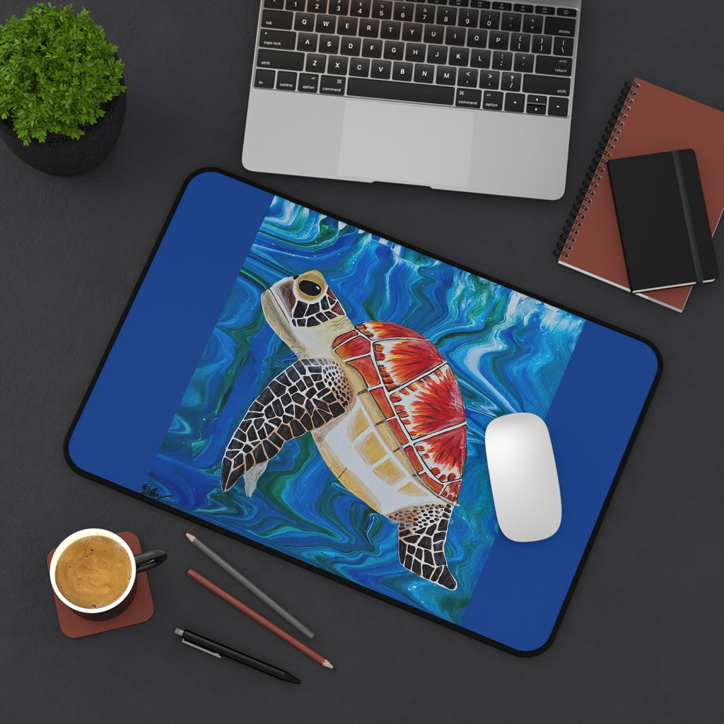 Colorful turtle design desk mat on a desk with laptop, mouse, and office supplies.