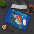 Colorful turtle design desk mat on a desk with laptop, mouse, and office supplies.