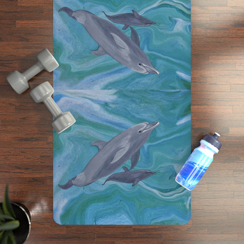 Yoga mat with dolphin design on a wooden floor with weights and a water bottle.