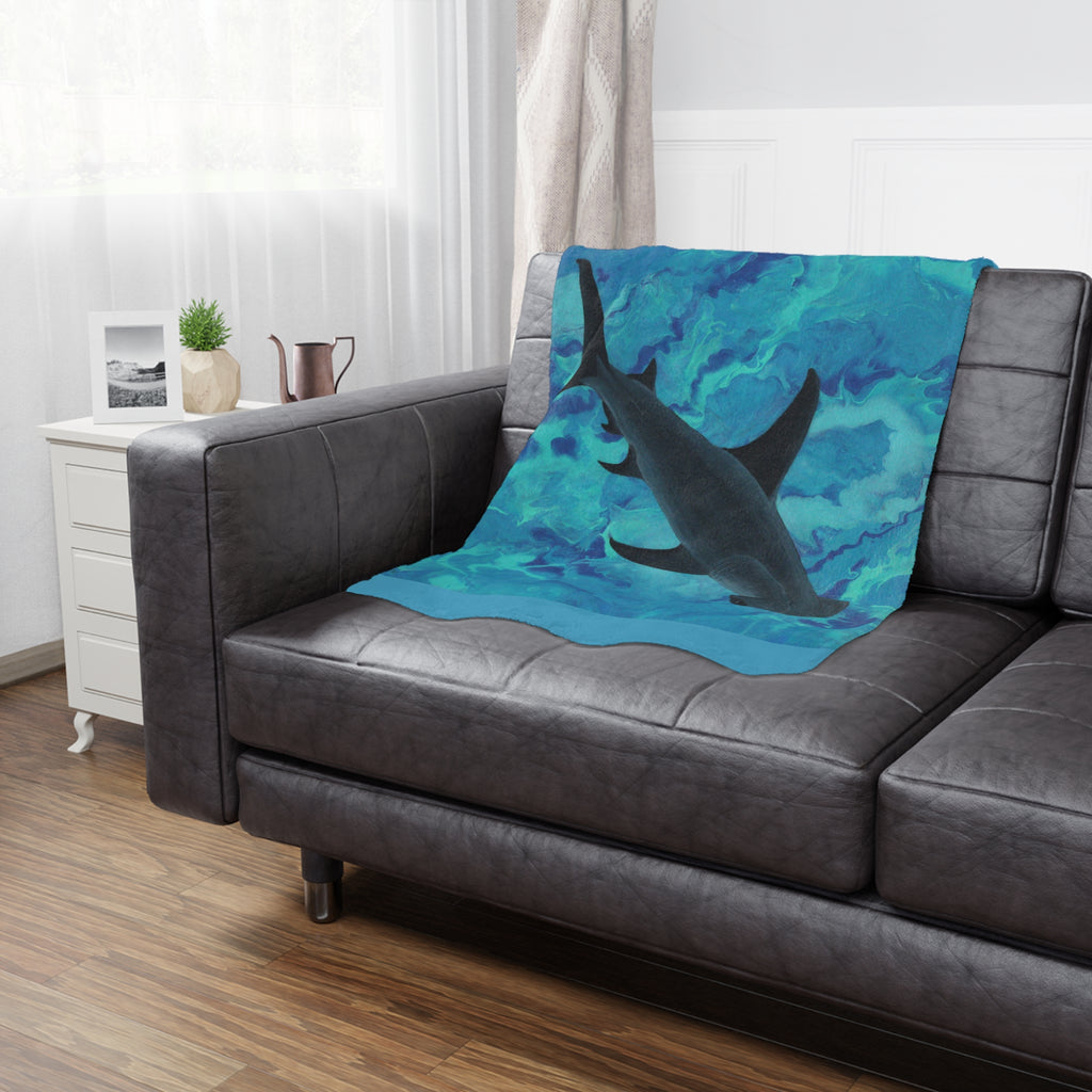 Shark-themed blanket draped over a gray sofa in a living room setting.
