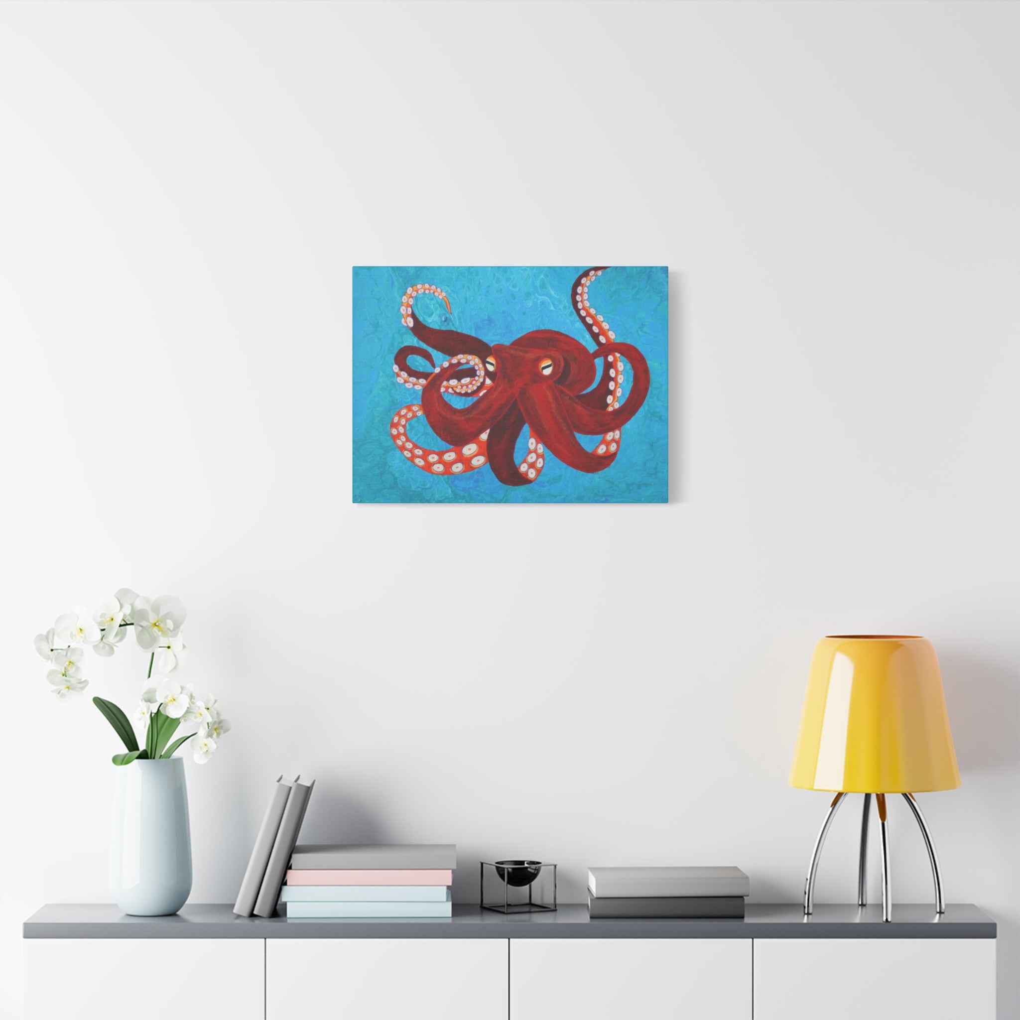 Red octopus painting on a blue background above a white shelf with decorative items.