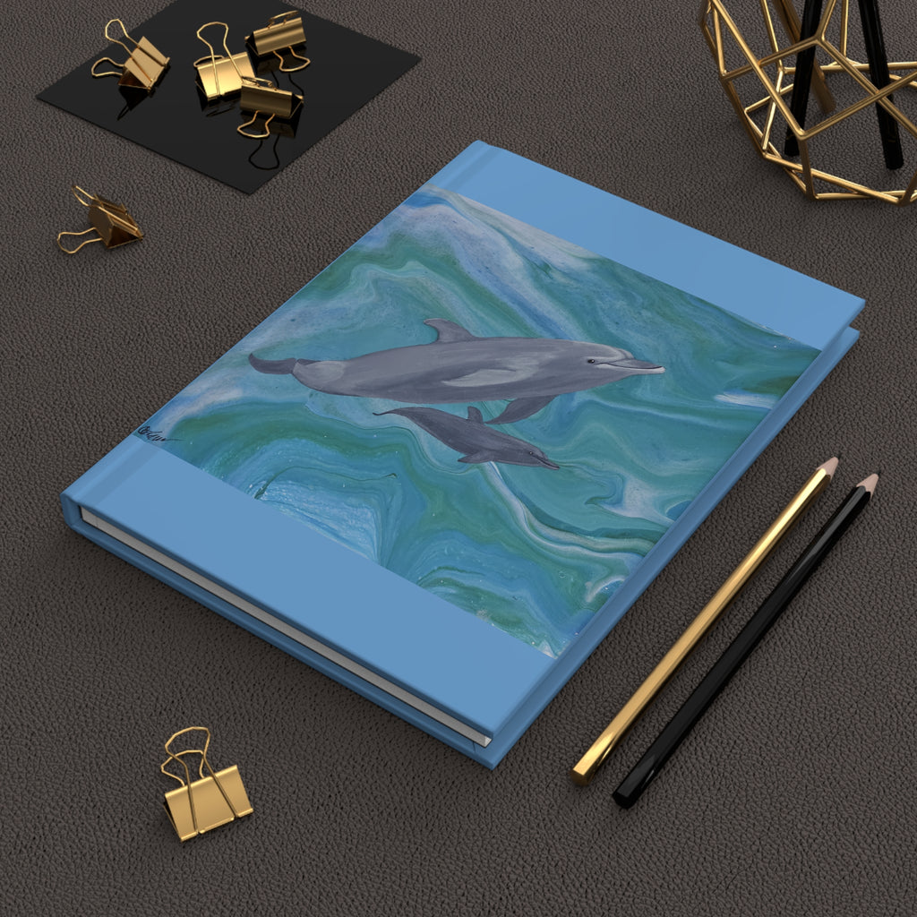 Notebook with dolphin design on a dark surface with office supplies