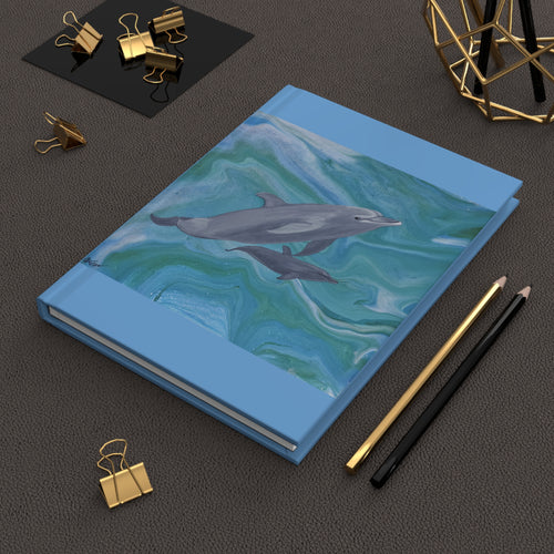 Notebook with dolphin design on a dark surface with office supplies