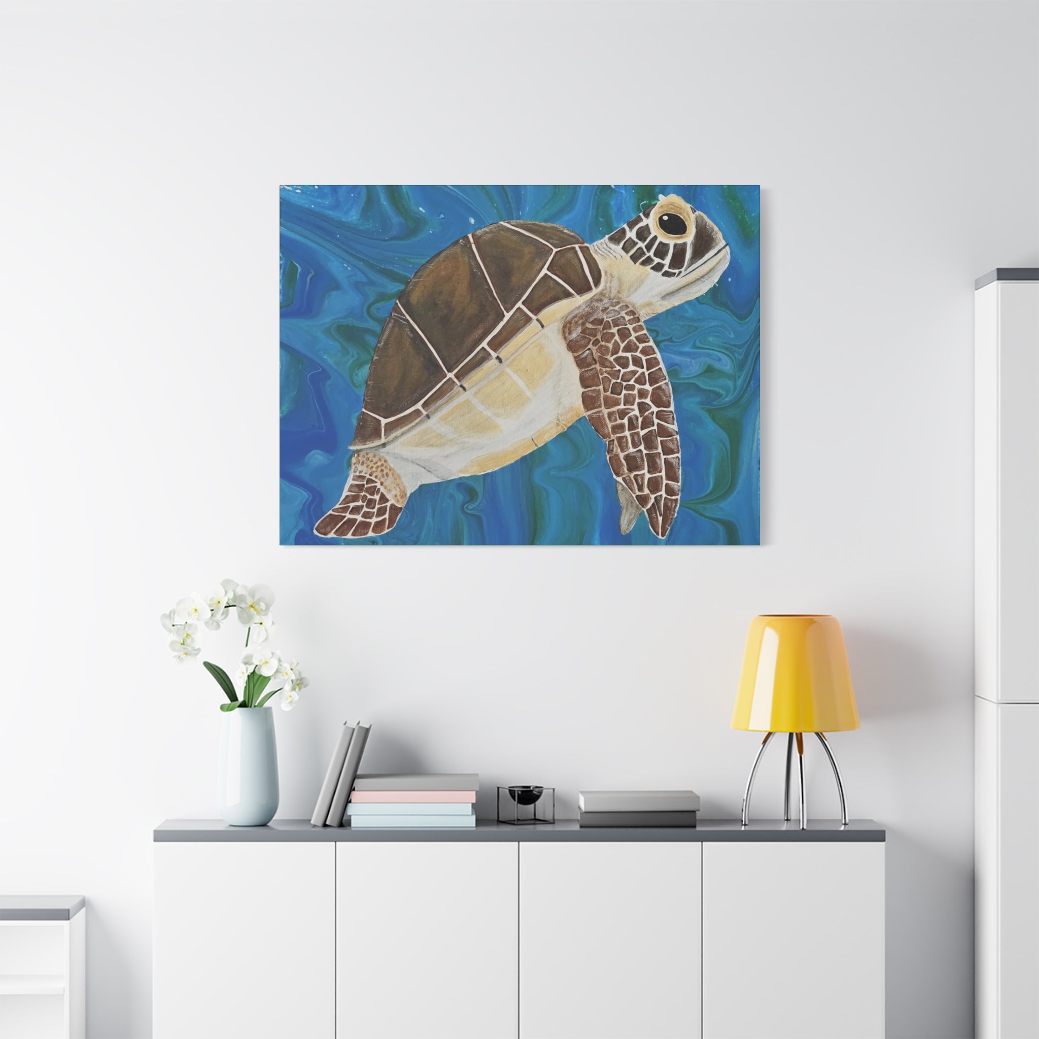 Painting of a turtle on a wall above a white cabinet with a yellow lamp and white flowers.