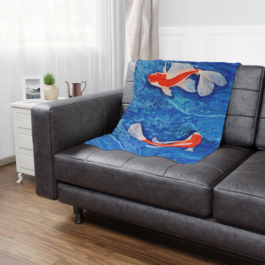 Decorative blanket with koi fish design on a gray sofa in a living room.