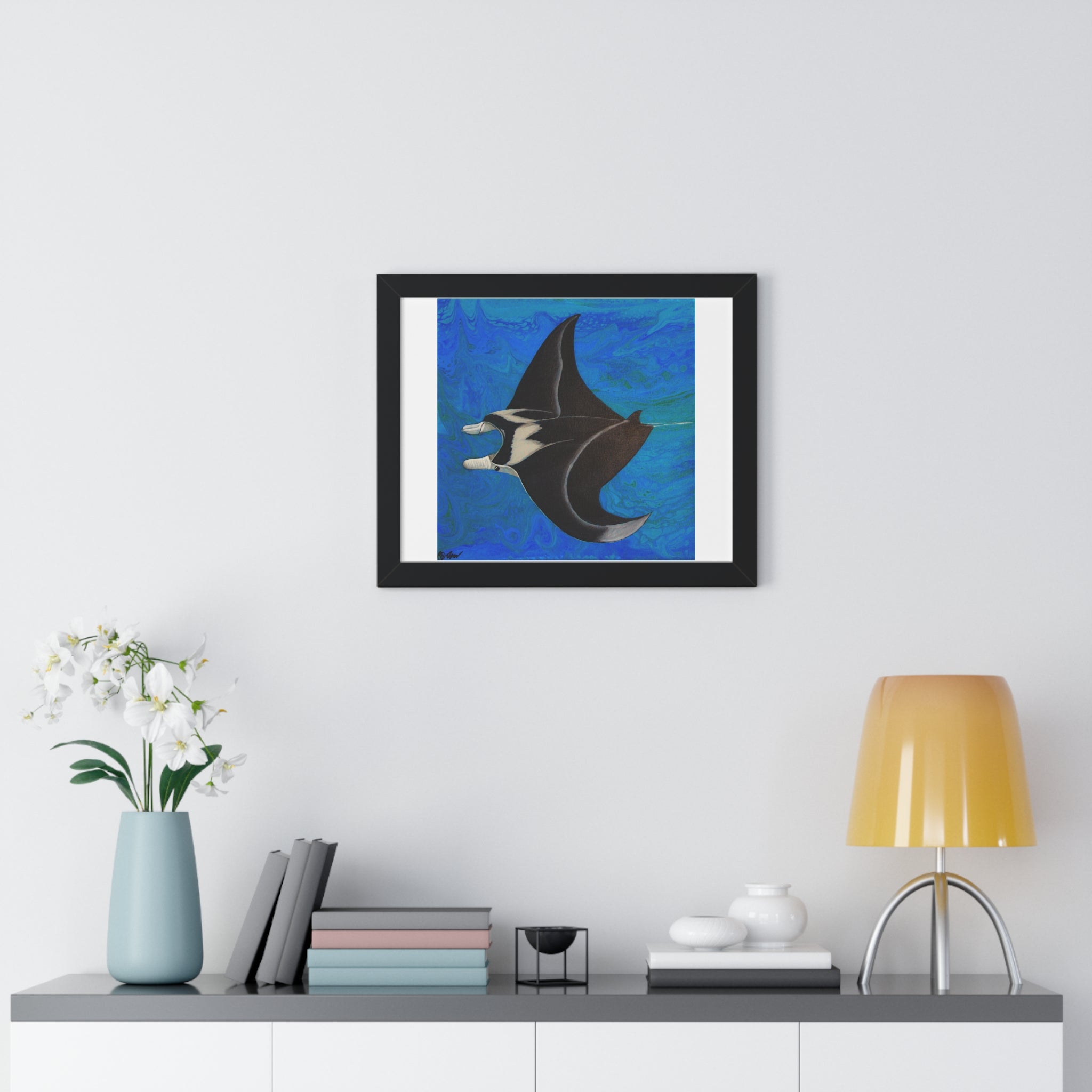 Framed artwork of a manta ray on a wall above a shelf with decor items.