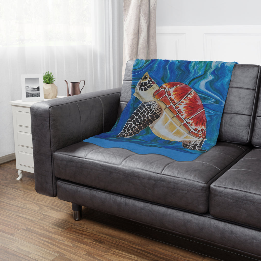 Colorful turtle blanket draped over a gray sofa in a living room.