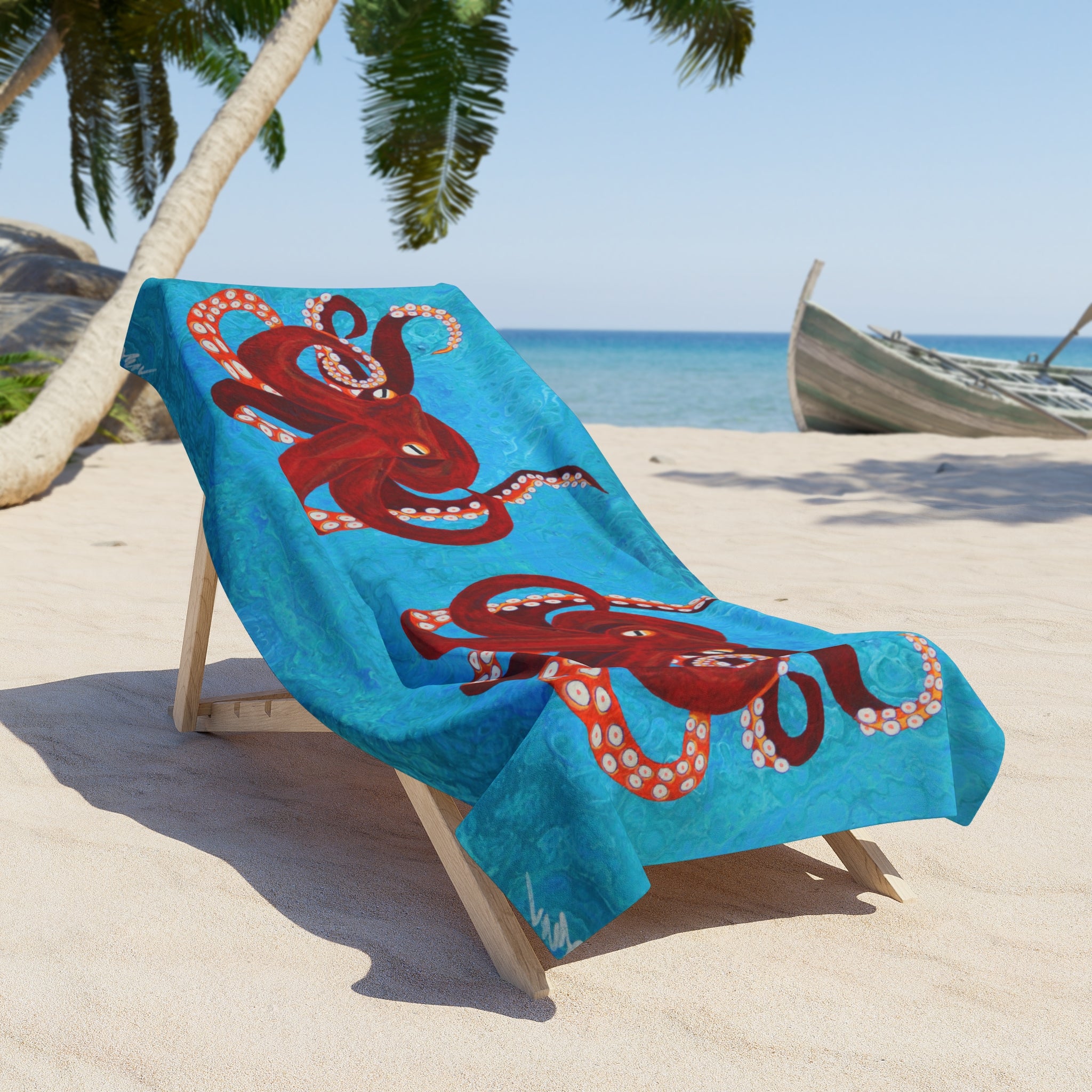 Blue beach towel/blanket with red octopus design on a wooden chair at a sandy beach.