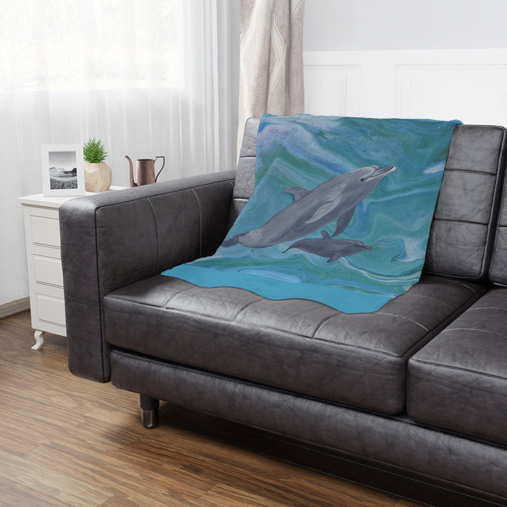 Gray sofa with a dolphin-themed blanket draped over it in a living room setting.