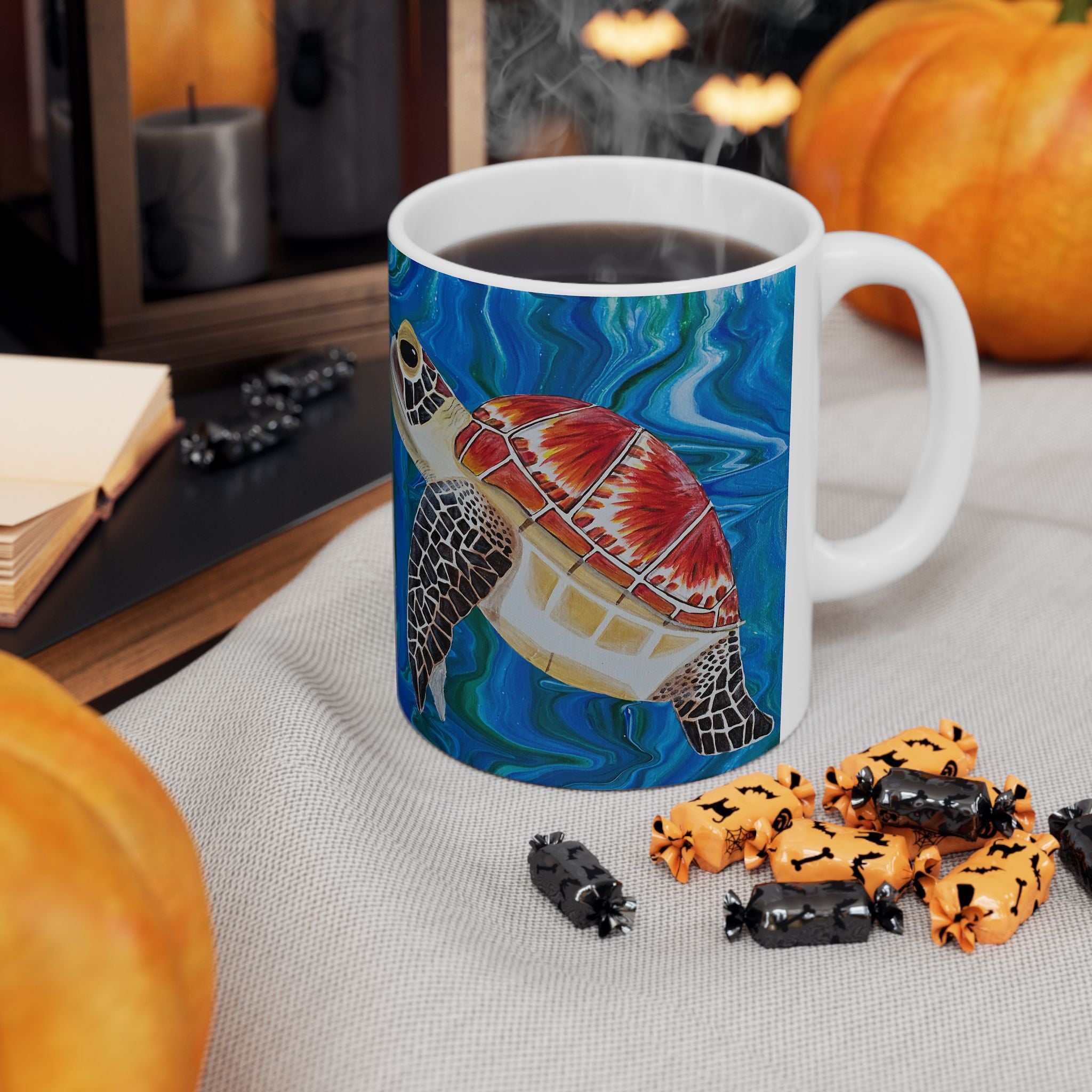 Mug with a turtle design on a table with Halloween-themed treats and pumpkins.