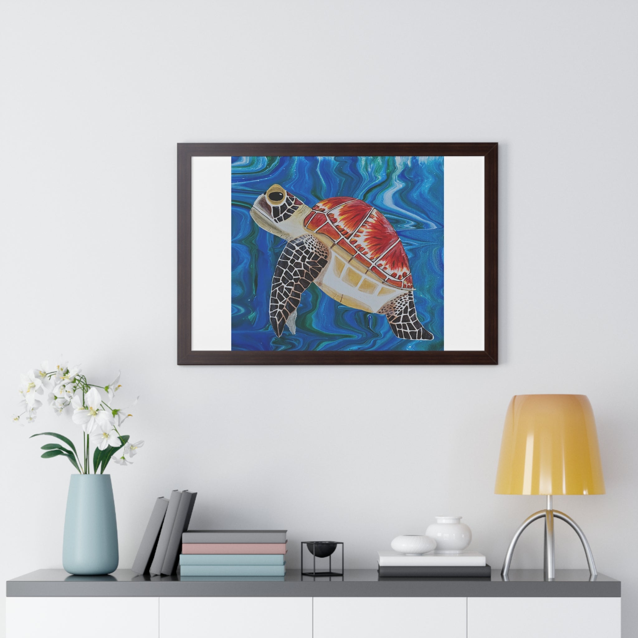 Framed artwork of a turtle with a tie-dye pattern on a wall above a shelf.