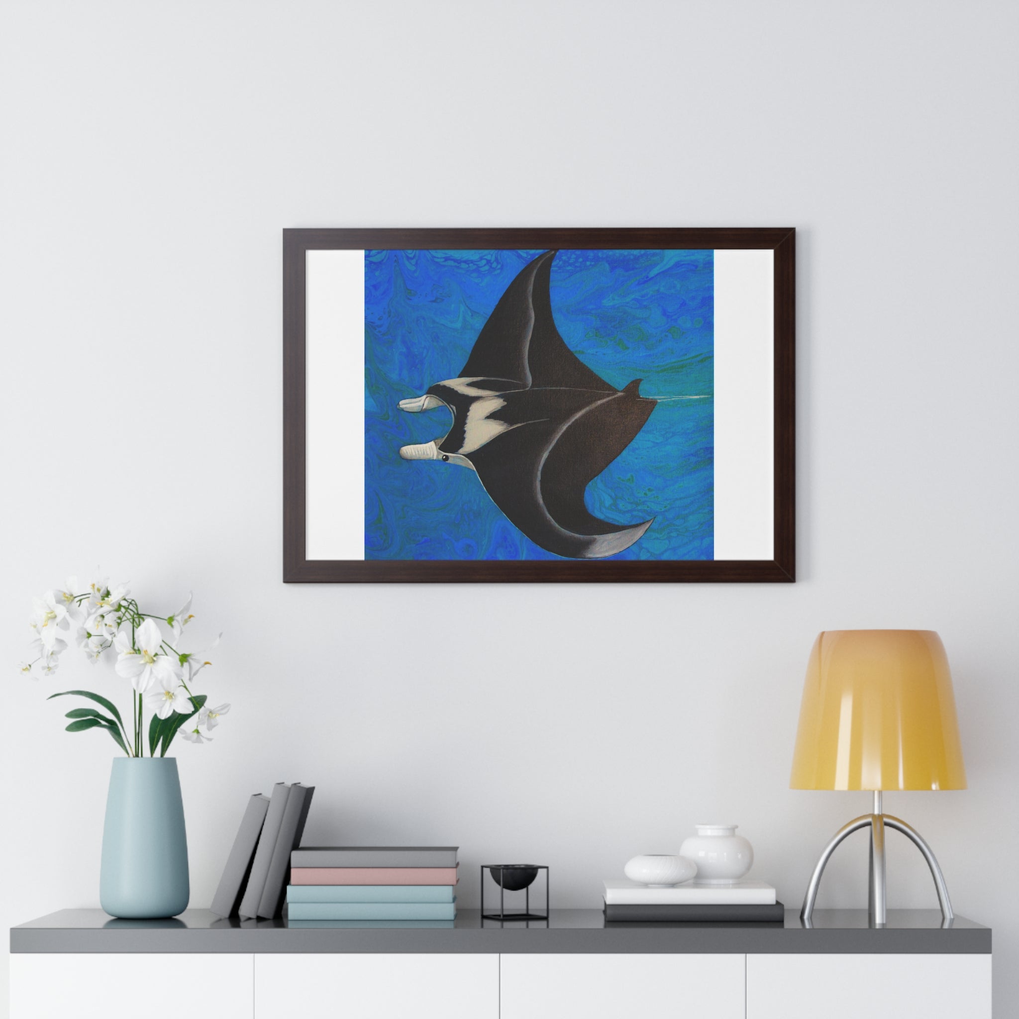 Framed artwork of a manta ray on a wall above a shelf with decor items.