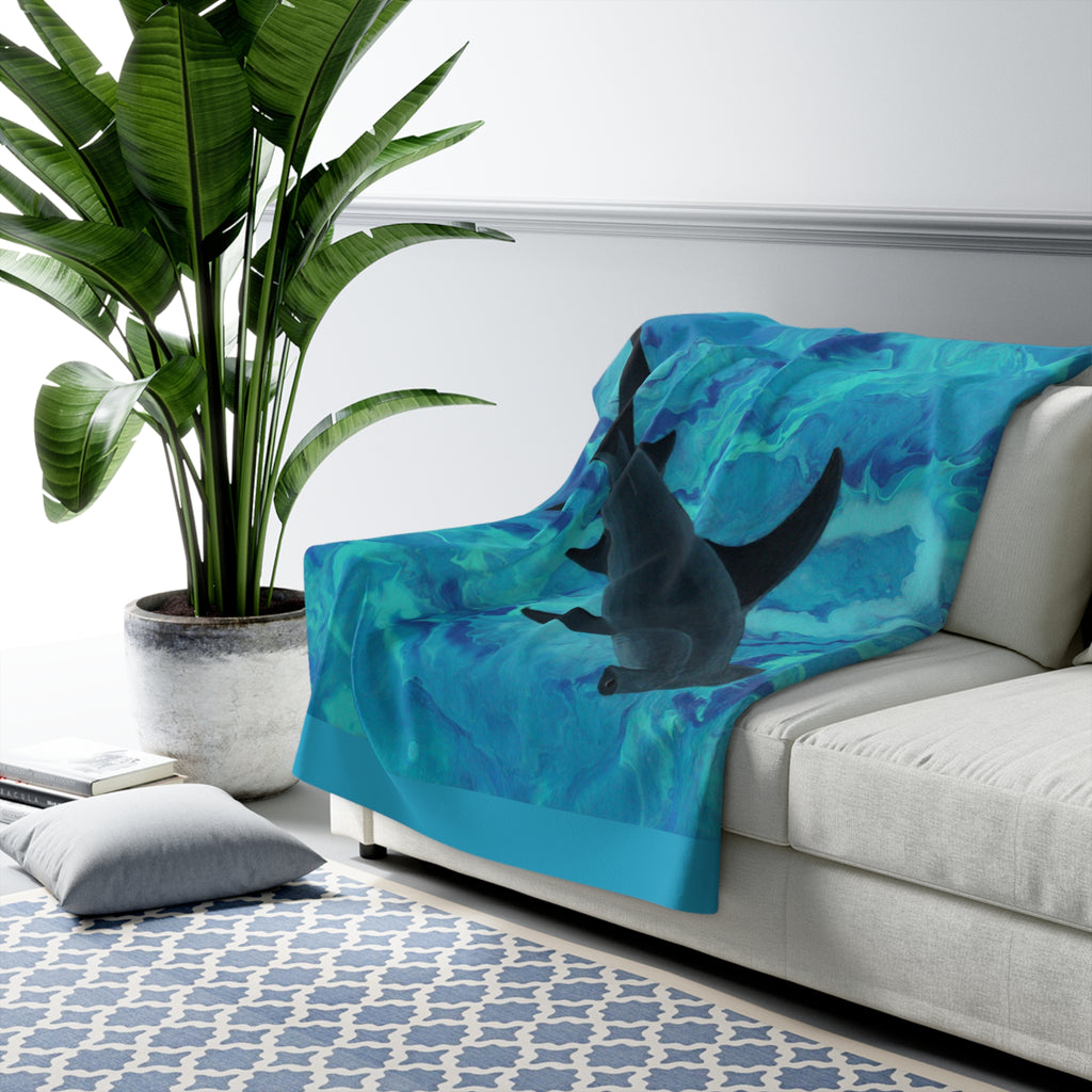 Blue blanket with shark design draped over a white couch in a living room setting.