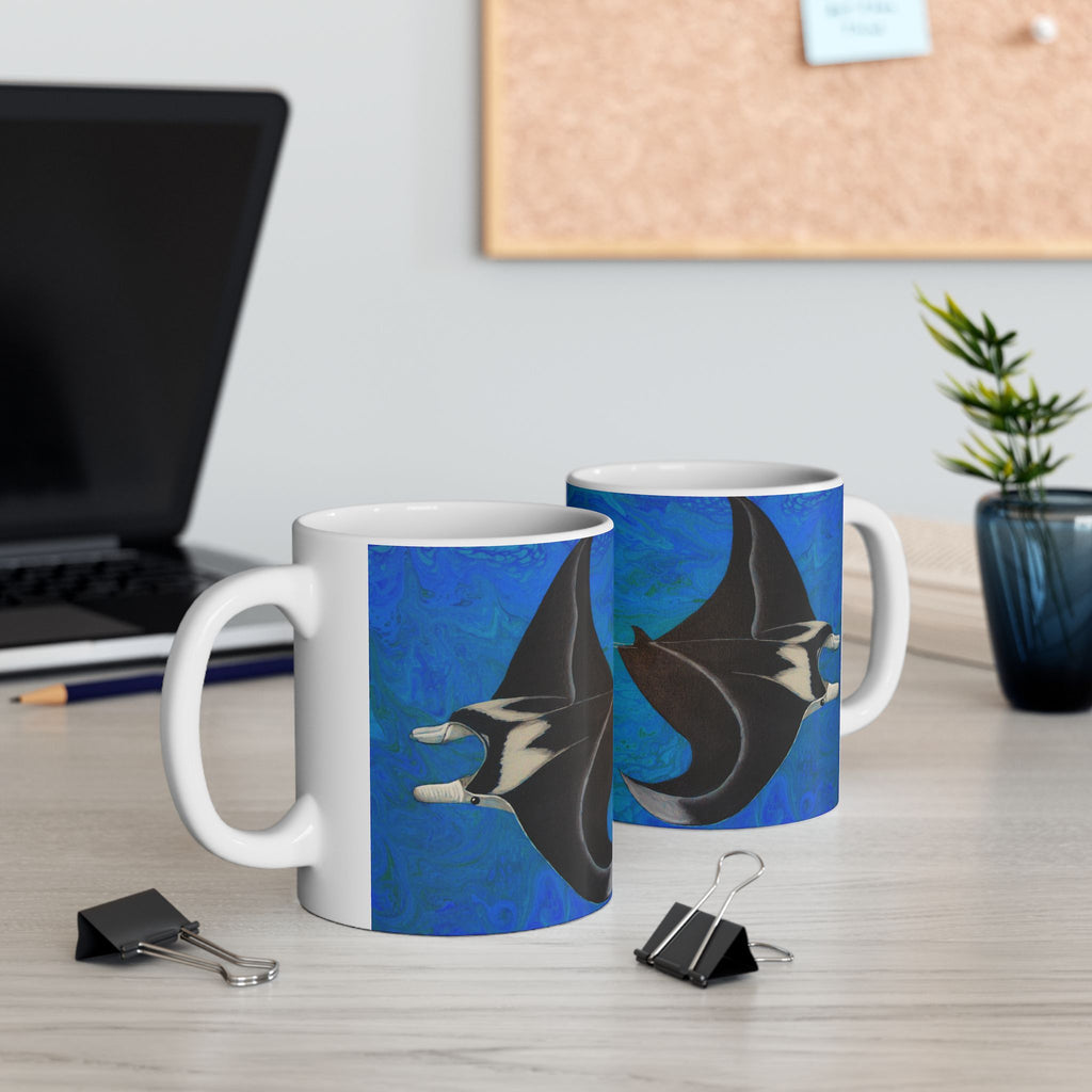 Two mugs with manta ray design on a desk with office supplies.