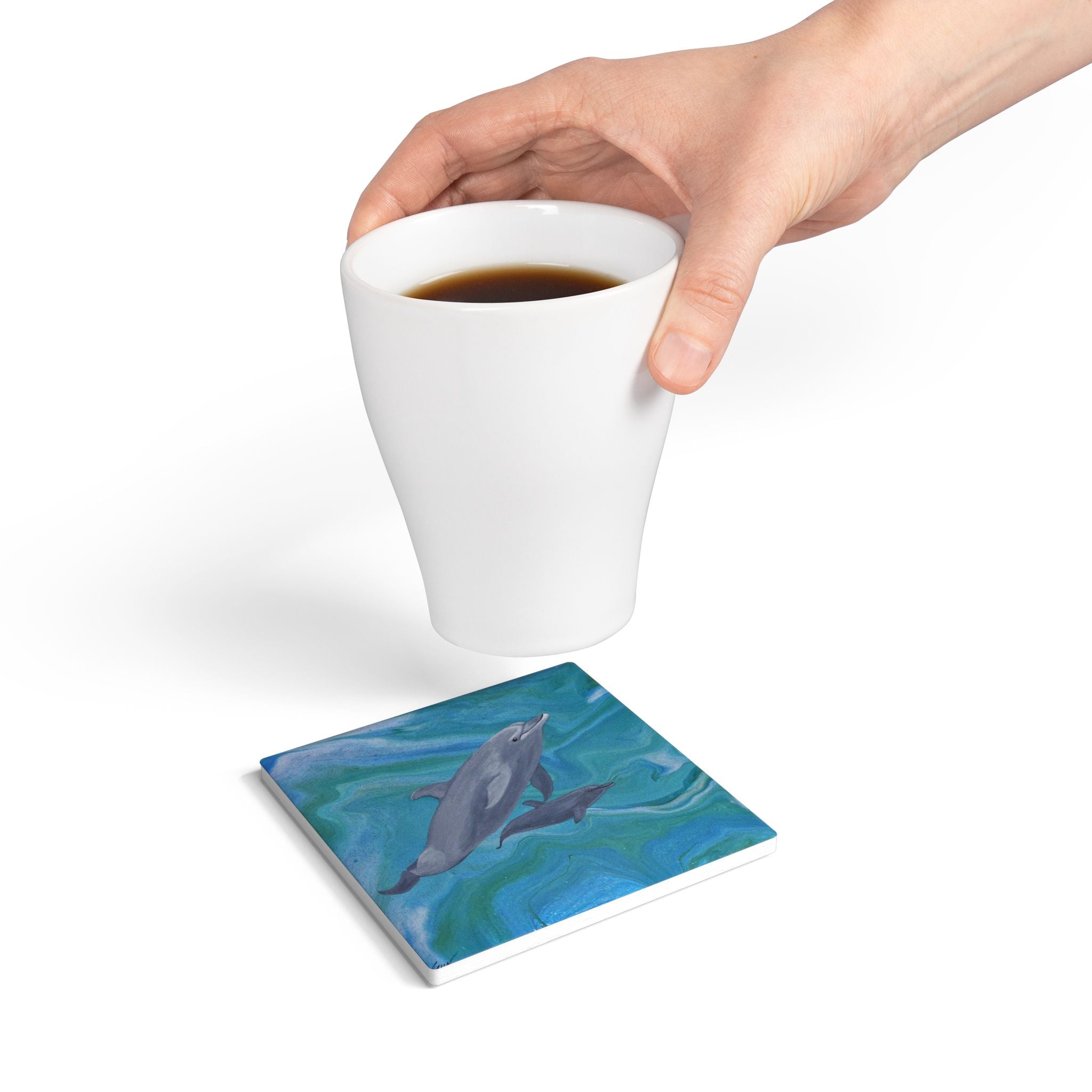Coaster with dolphin design under a white cup of coffee