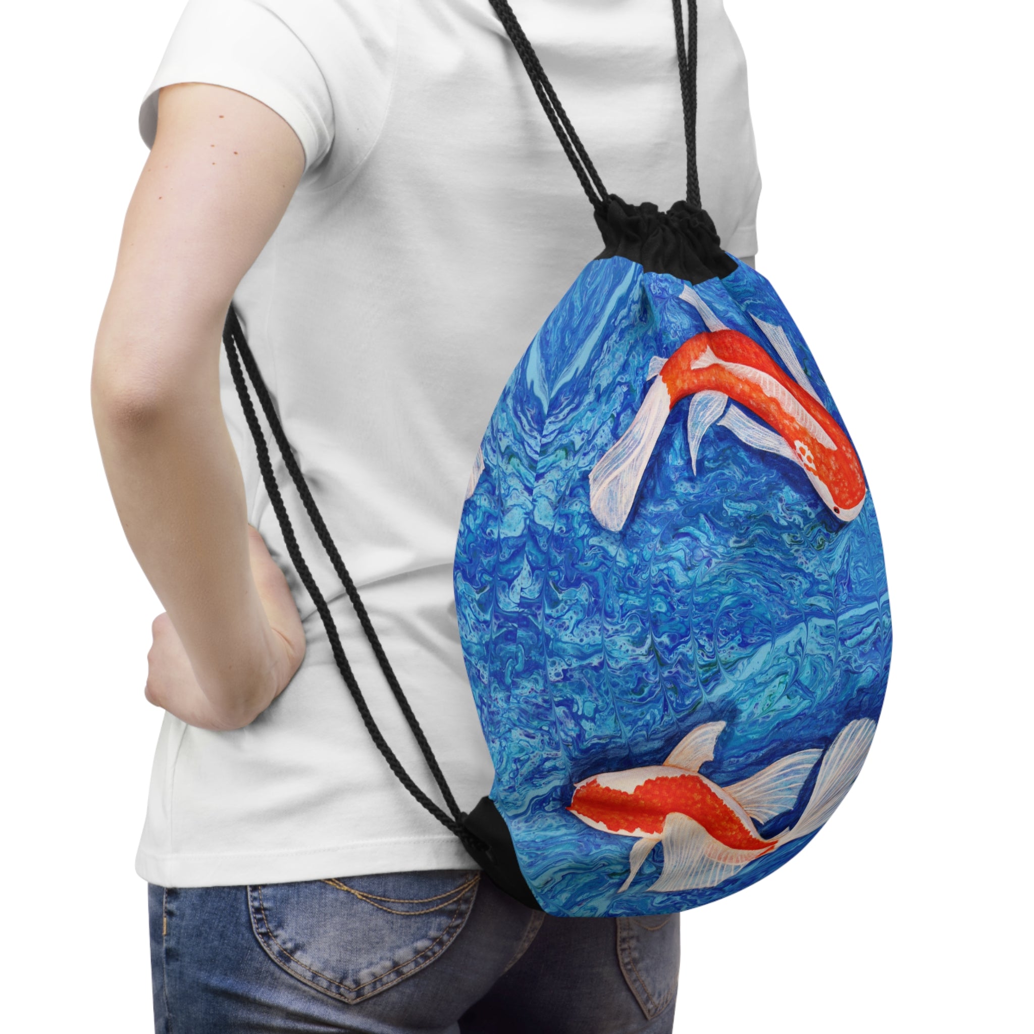 Drawstring bag with koi fish design held by a person wearing a white shirt and jeans.