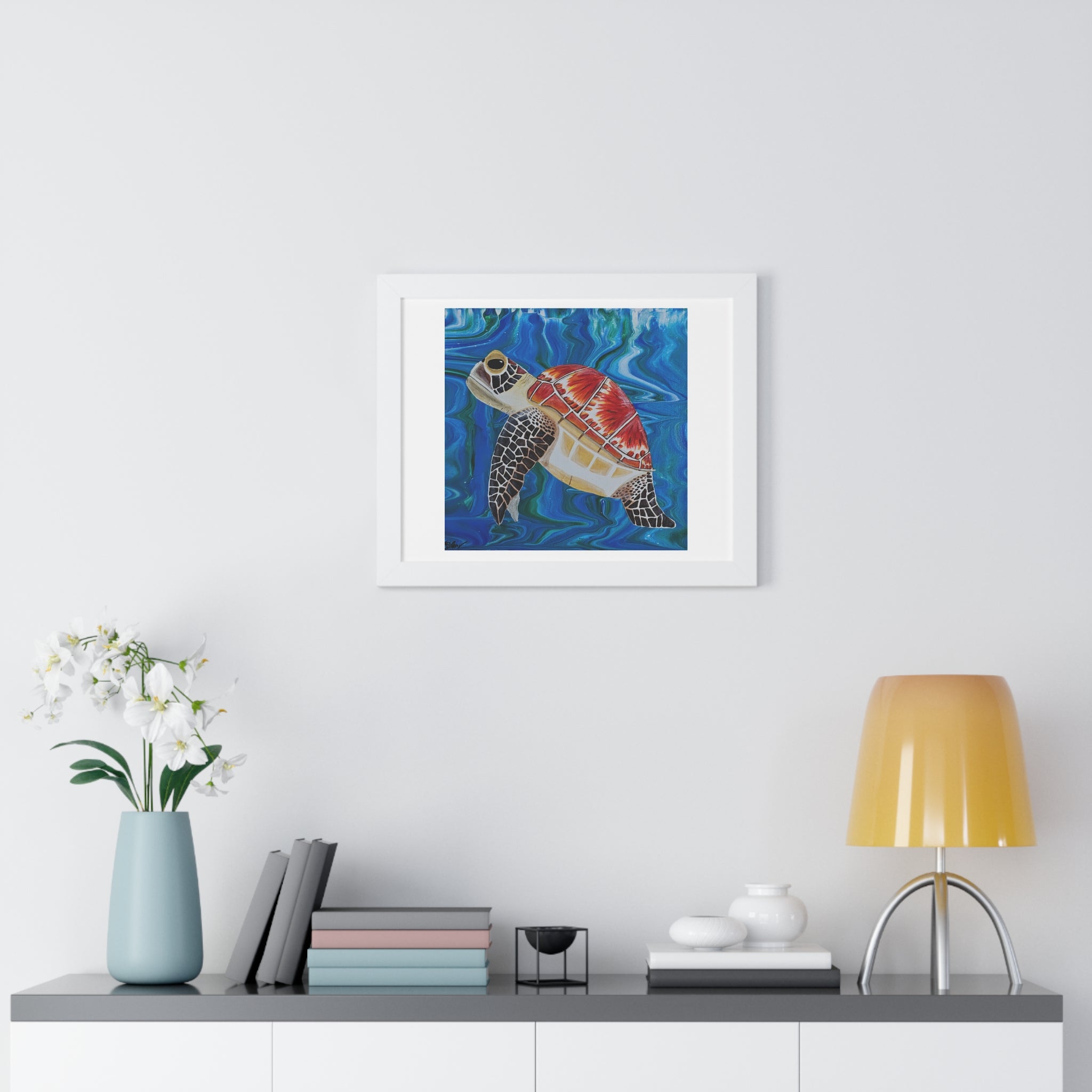 Framed artwork of a turtle on a wall above a shelf with decor items.