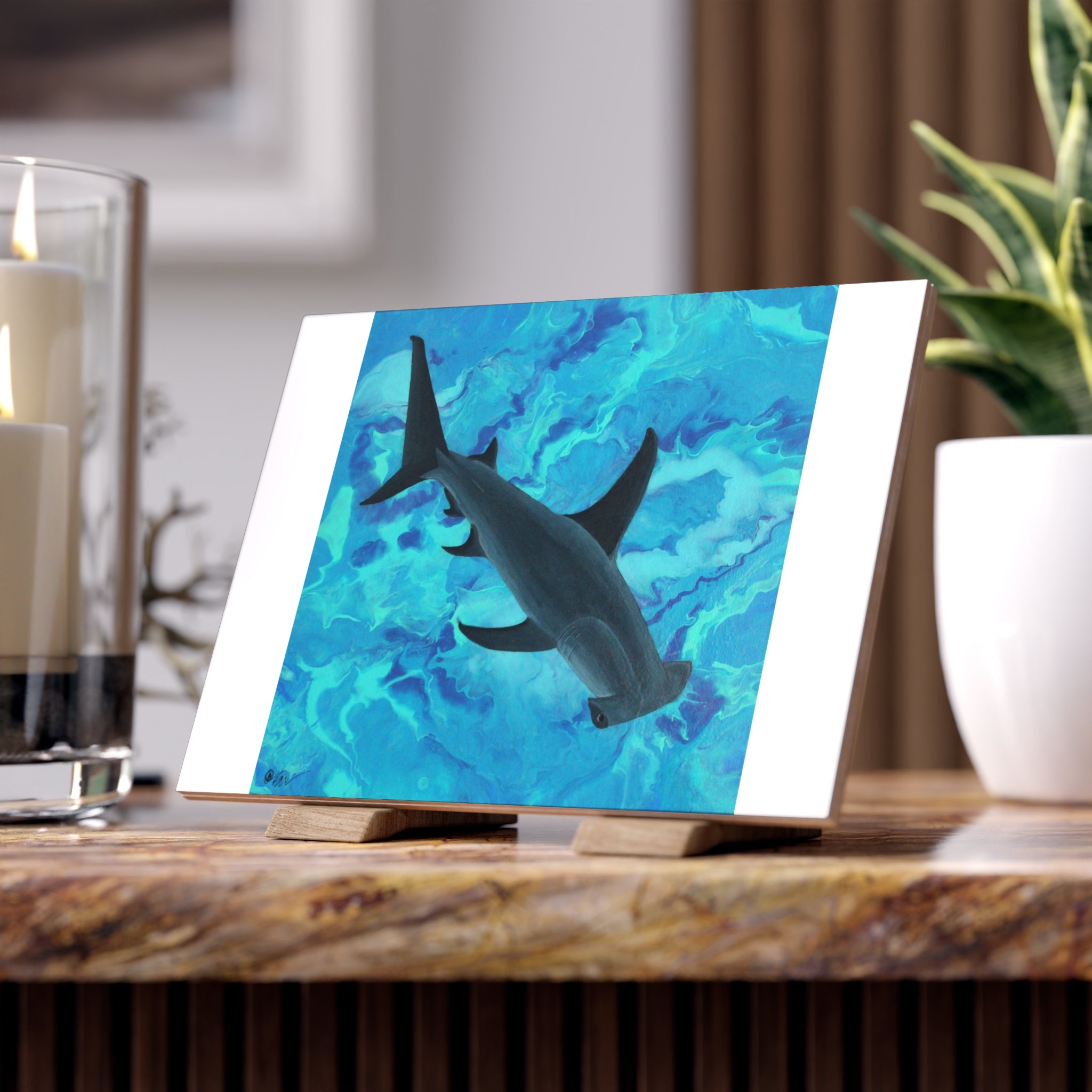Desk with a shark tile on an easel, candles, and a plant in the background.