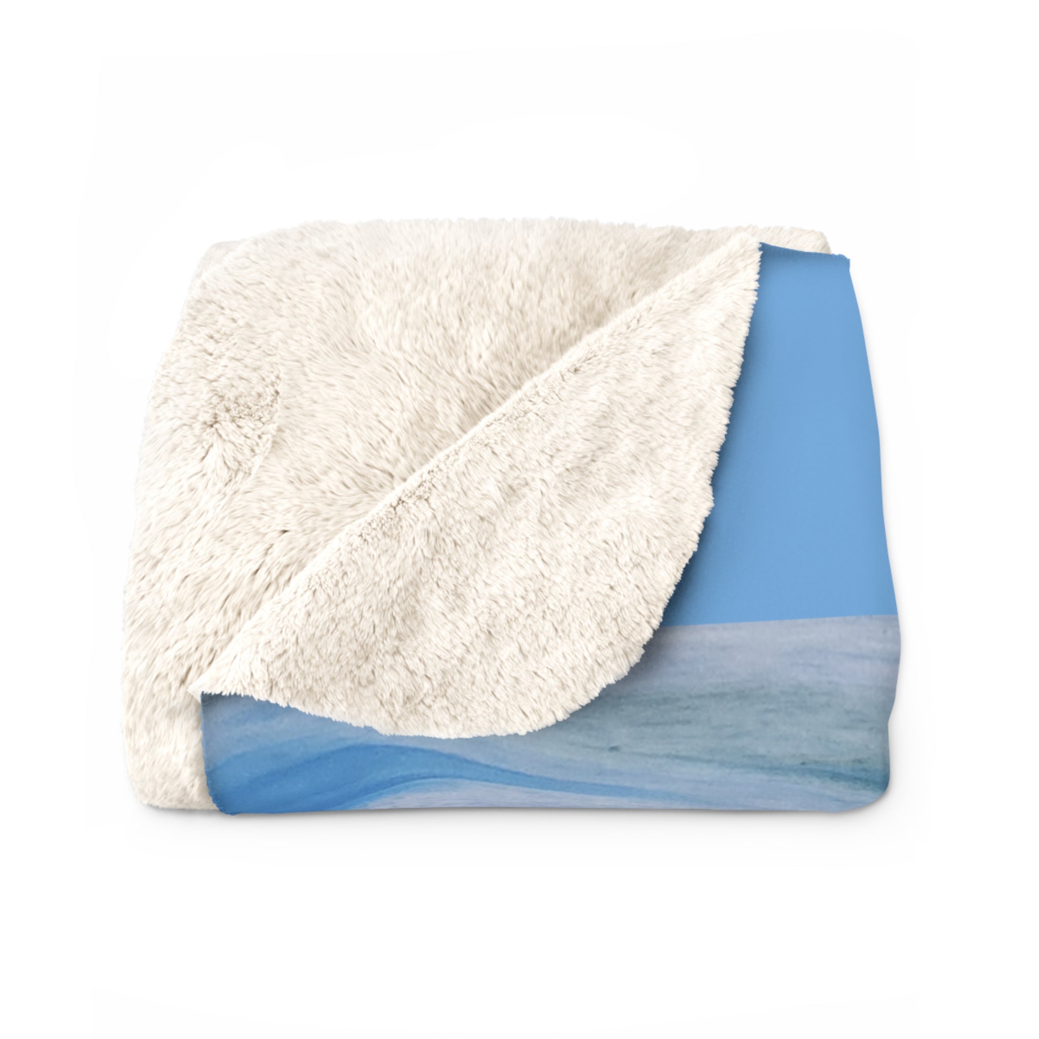 Folded blanket with white sherpa side and blue patterned side on a white background