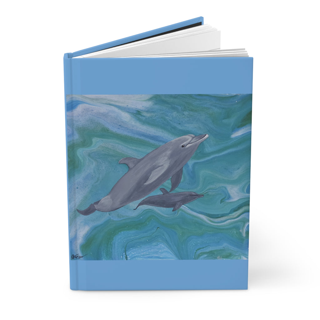 Notebook with dolphin illustration on a blue and green watercolor background