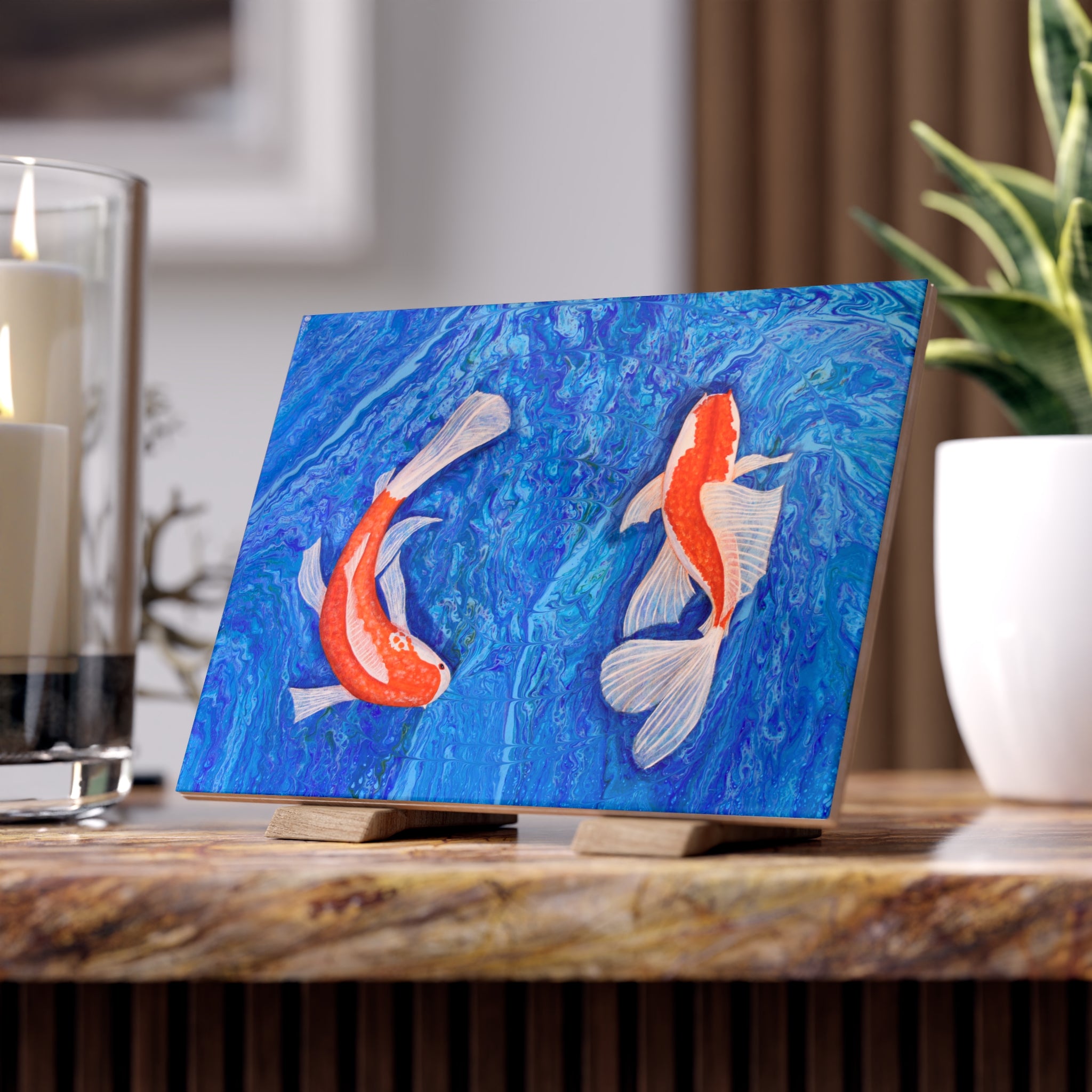 Decorative tile with koi fish on a blue background on a wooden surface.