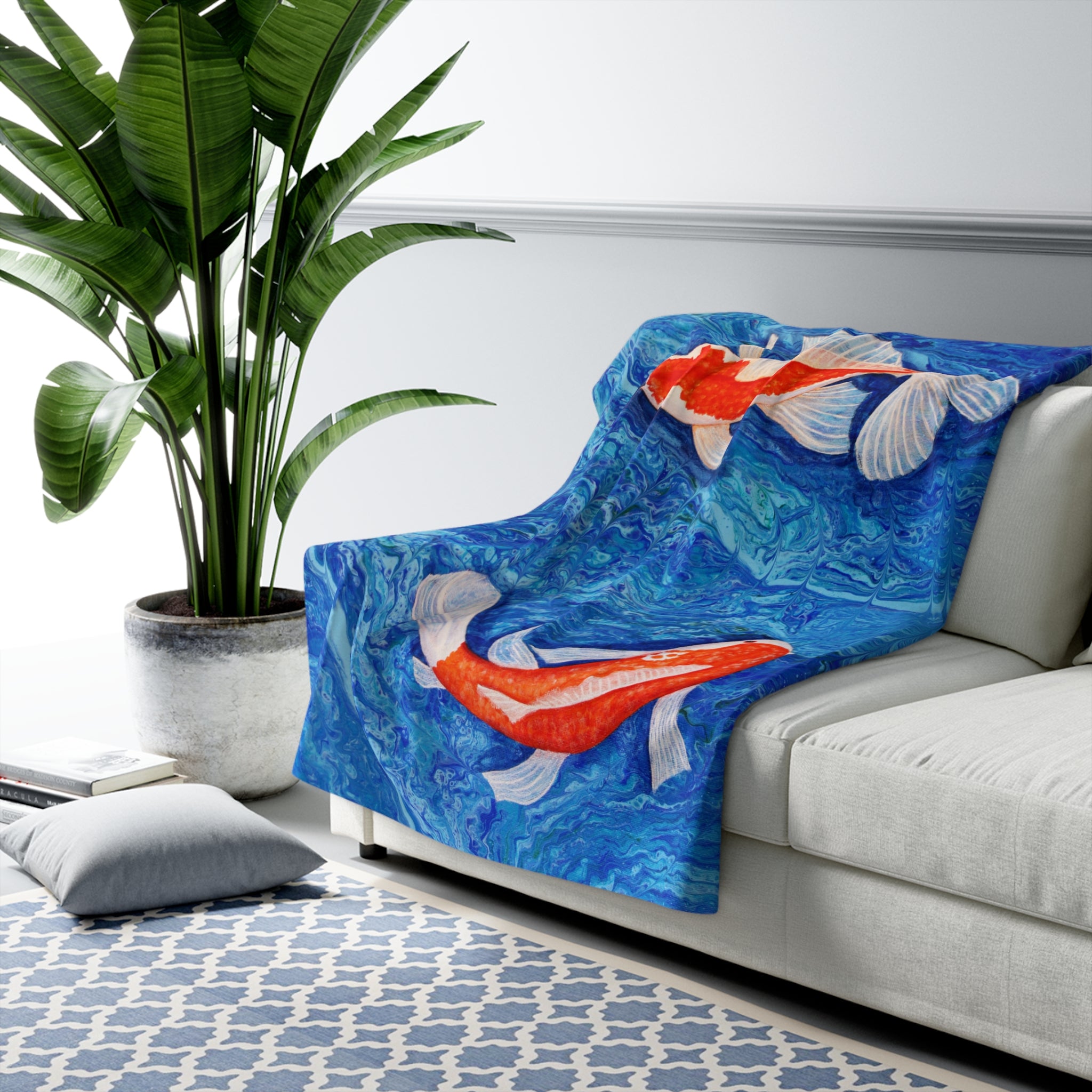 Blue blanket with fish design draped over a white sofa in a living room.