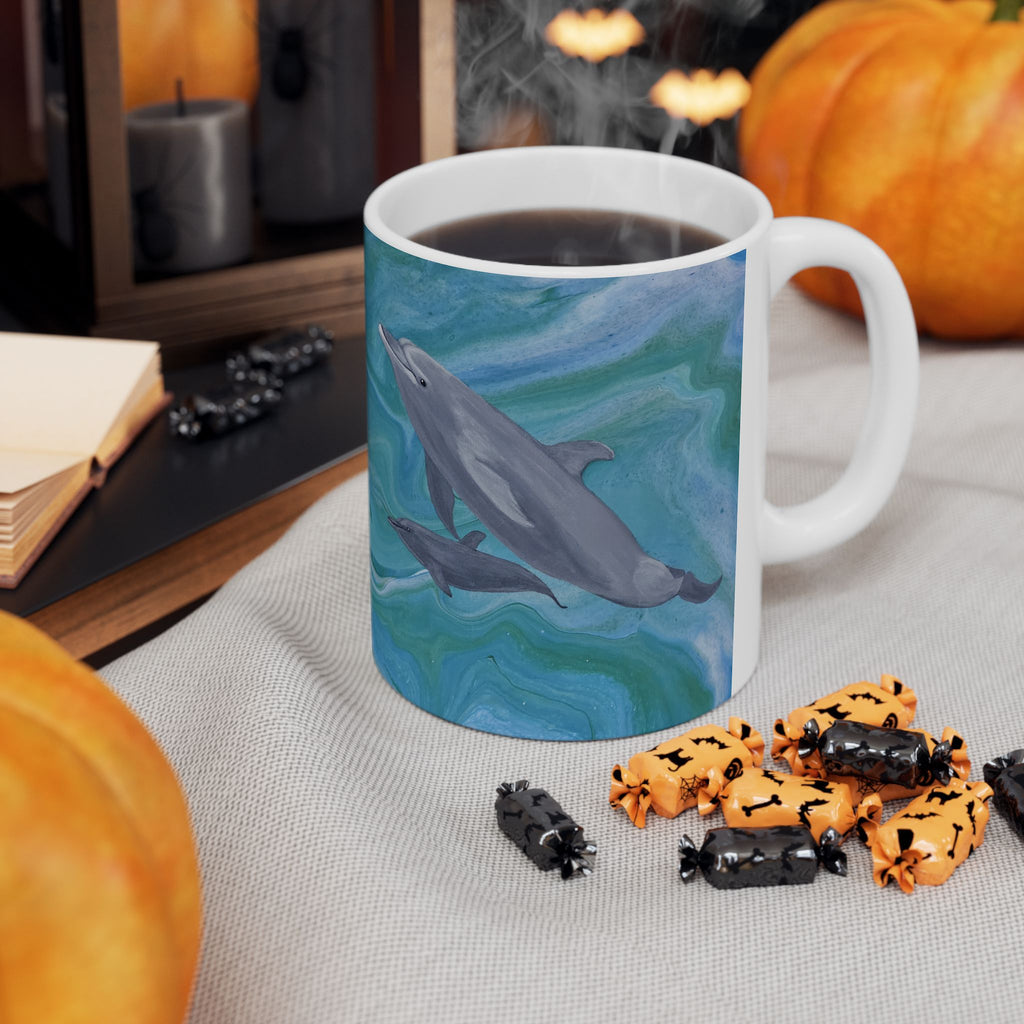 Mug with dolphin design on a table with Halloween treats and pumpkins.
