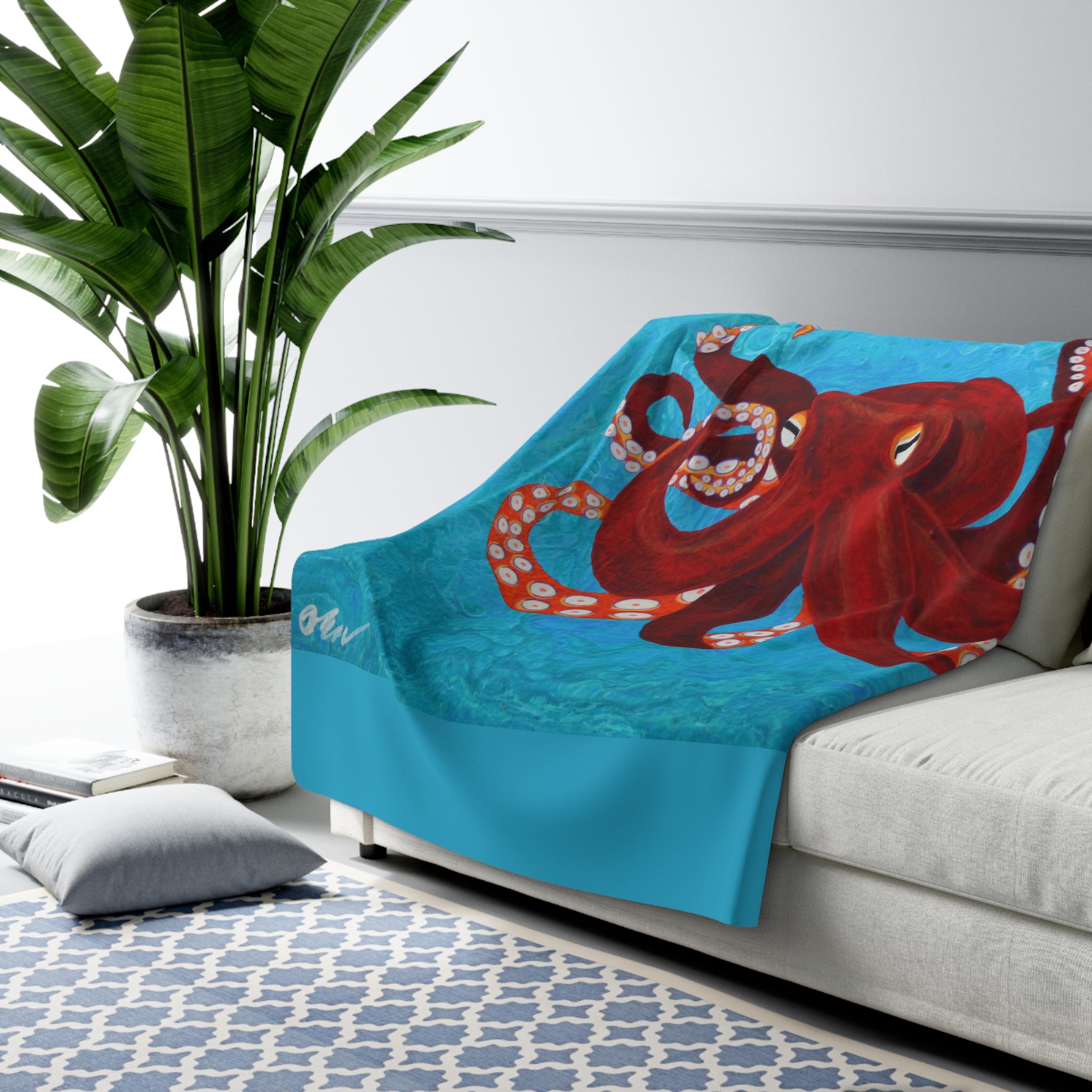Blue blanket with a red octopus design draped over a gray sofa in a living room.