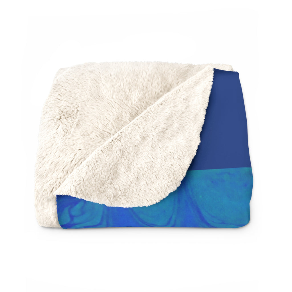 Folded blanket with white sherpa side and blue watercolor pattern on a white background