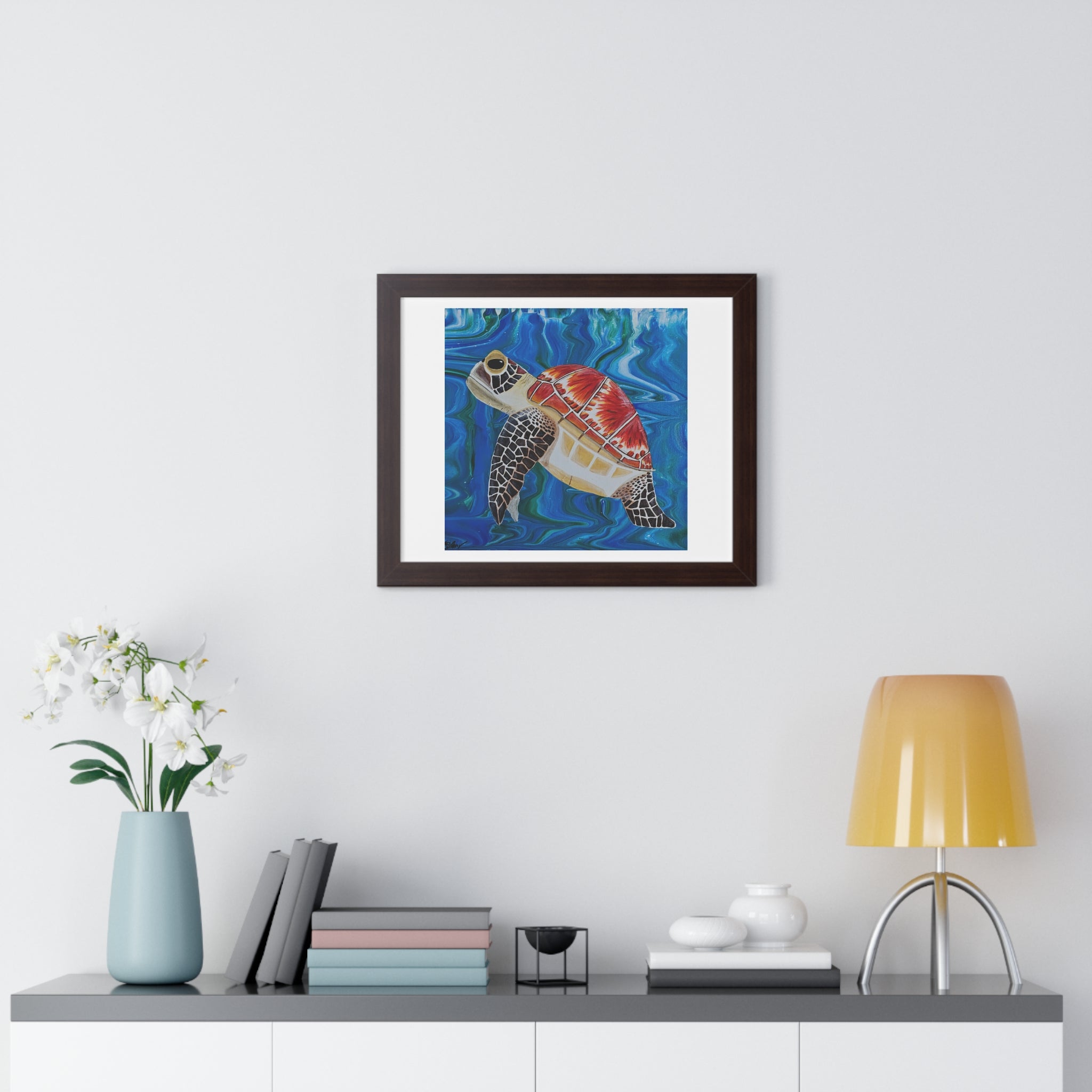Framed artwork of a turtle on a wall above a shelf with decor items.