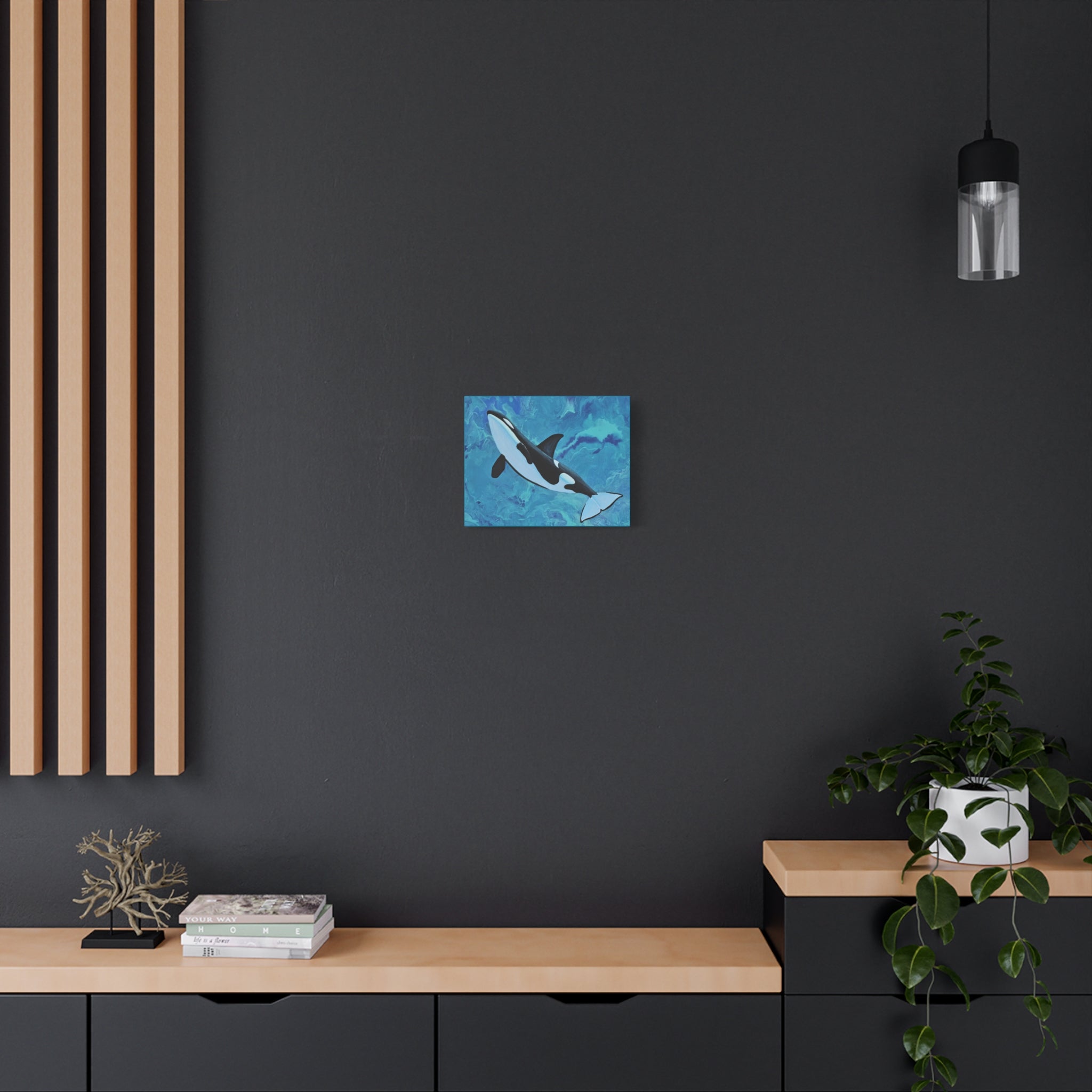 Abstract blue and orca whale canvas print on a dark wall with wooden shelves and decor.
