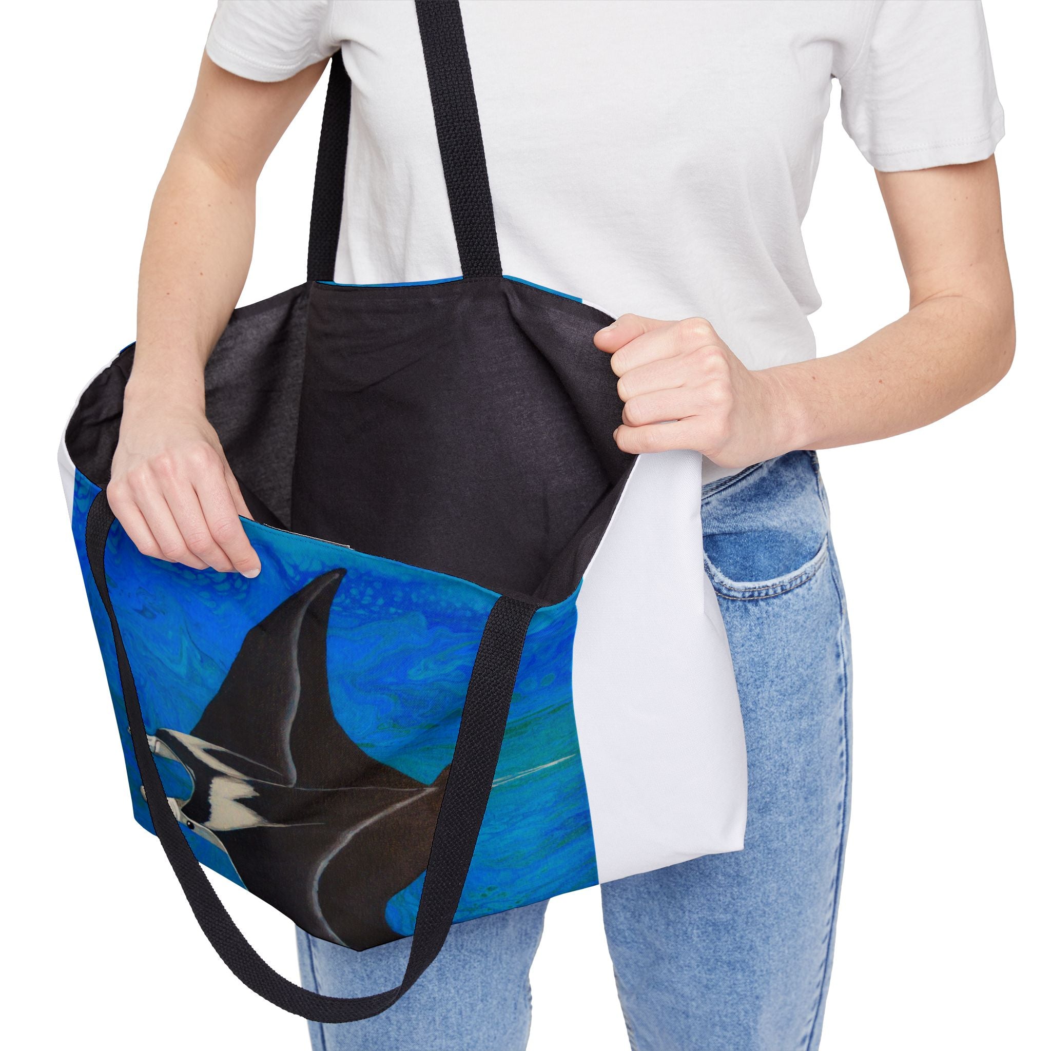 Person holding a blue tote bag with a manta ray design on a white background