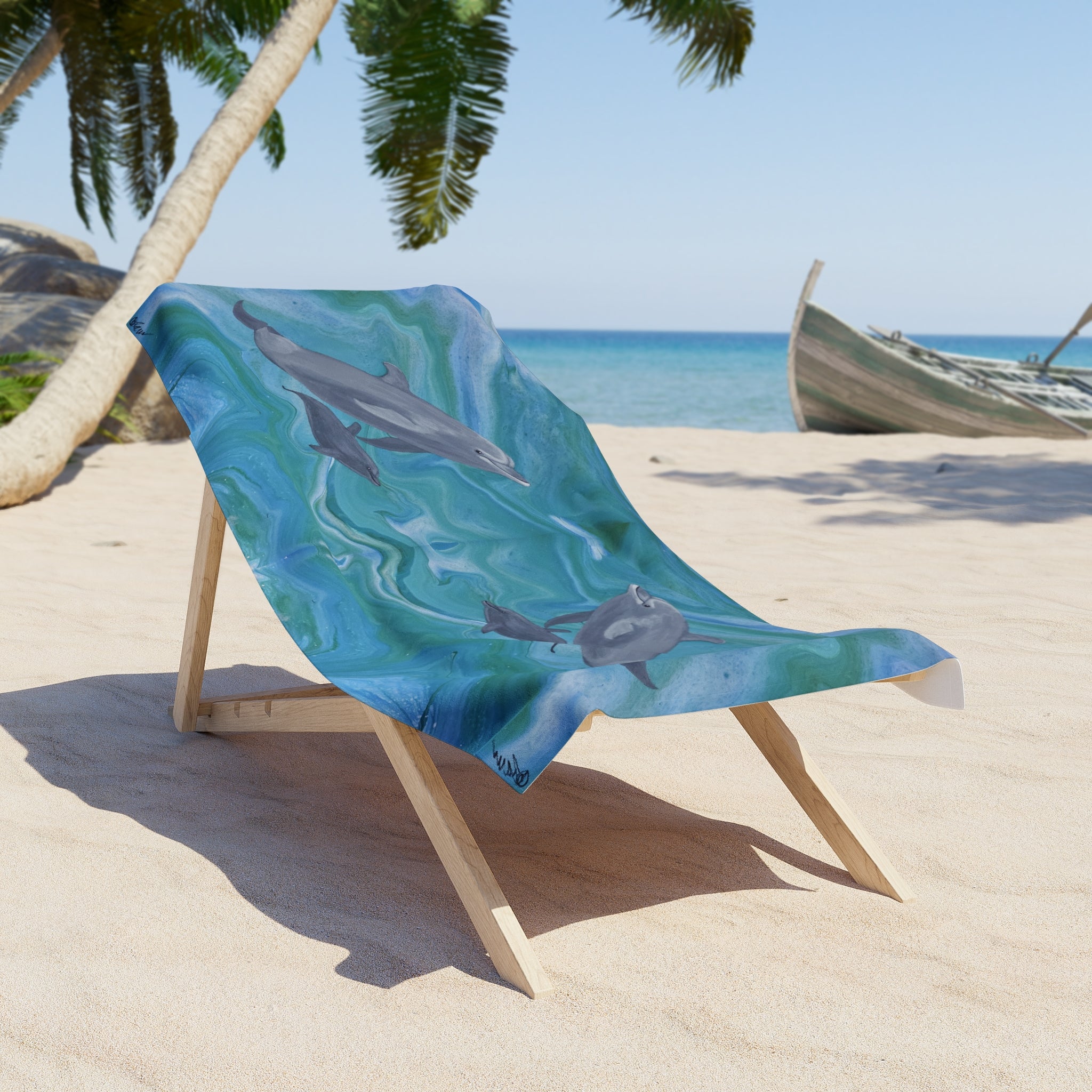 Beach chair with a dolphin-themed towel/blanket draped over it on a sandy beach.