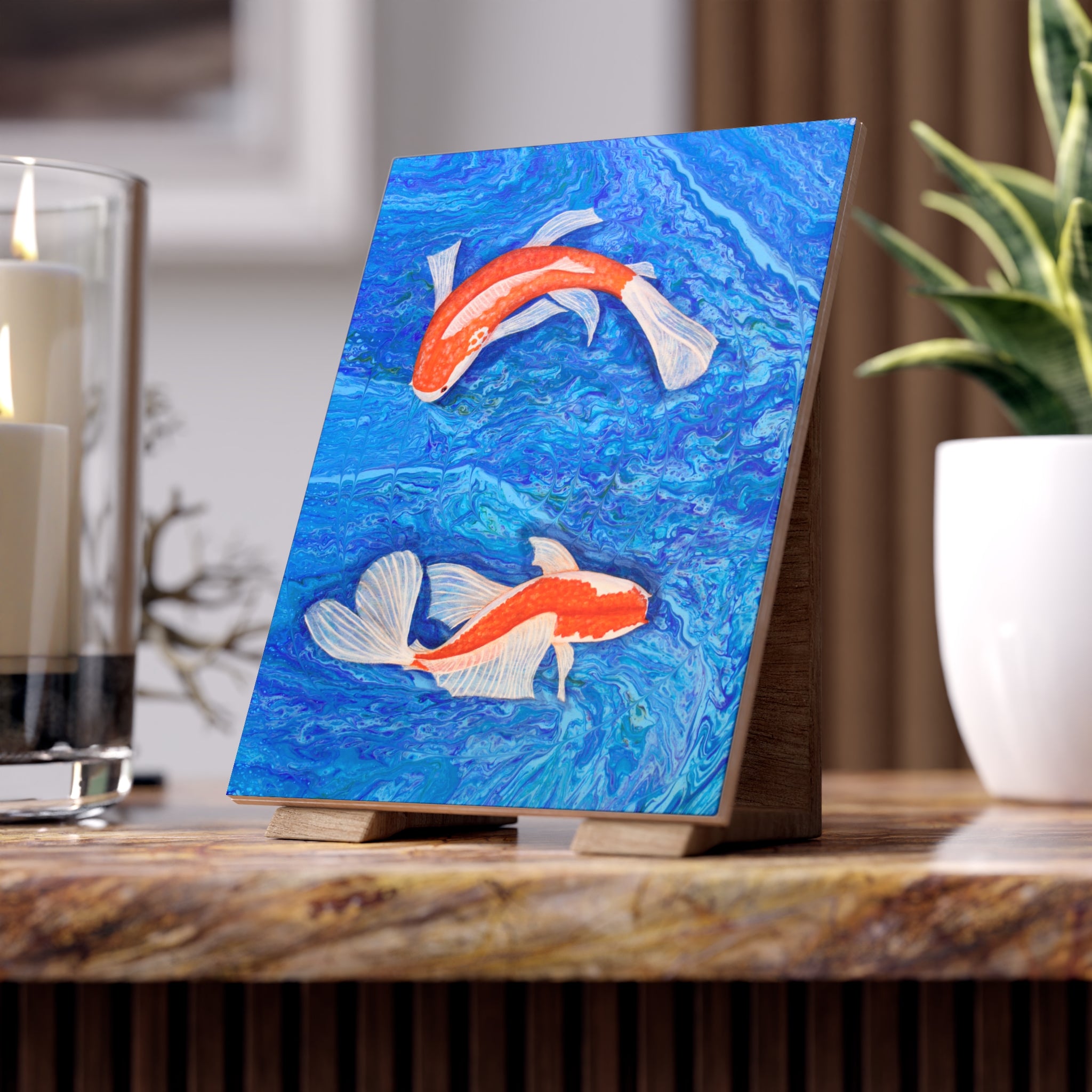 Artistic depiction of two koi fish on a blue background tile, displayed on a wooden stand.