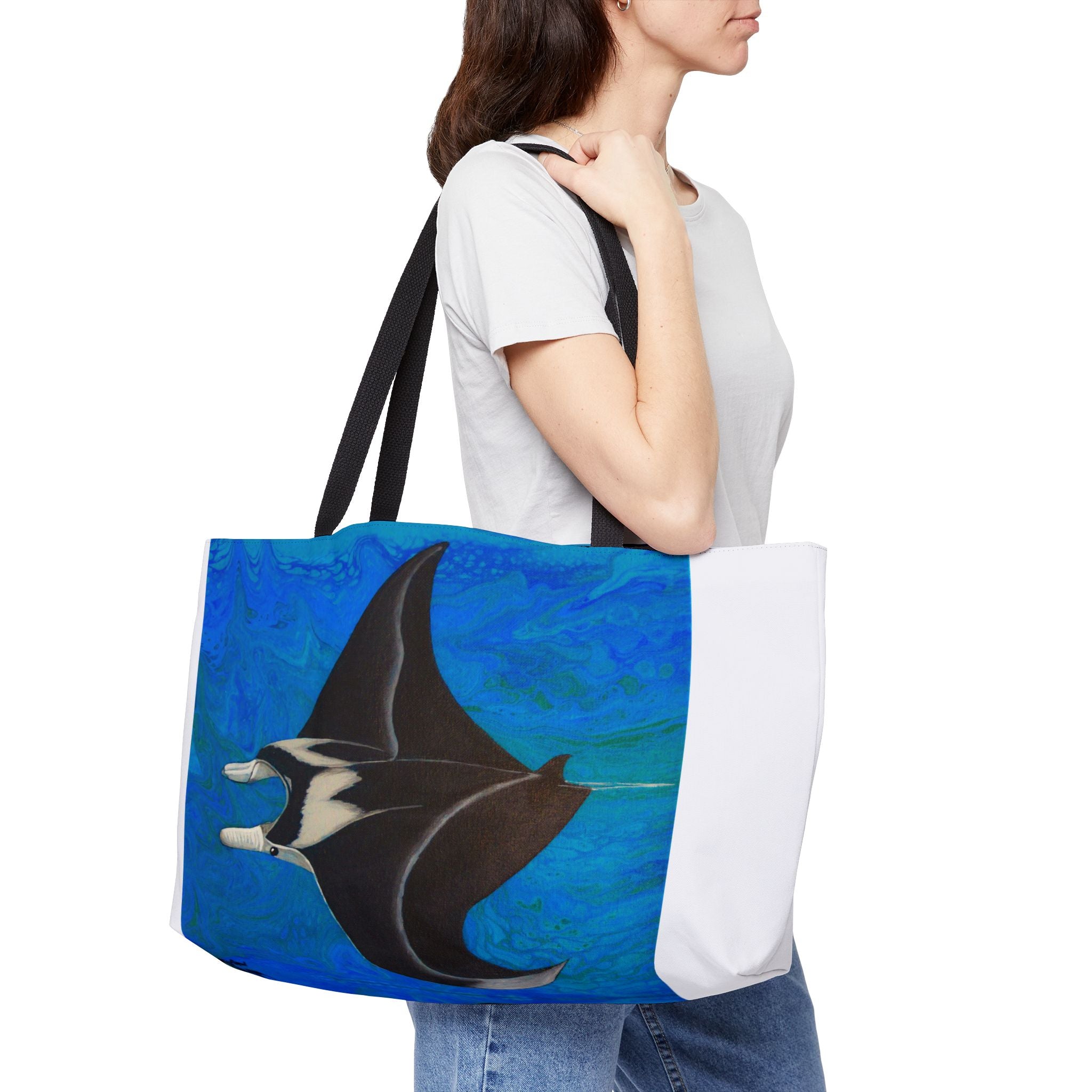 Person holding a tote bag with a manta ray design on a white background