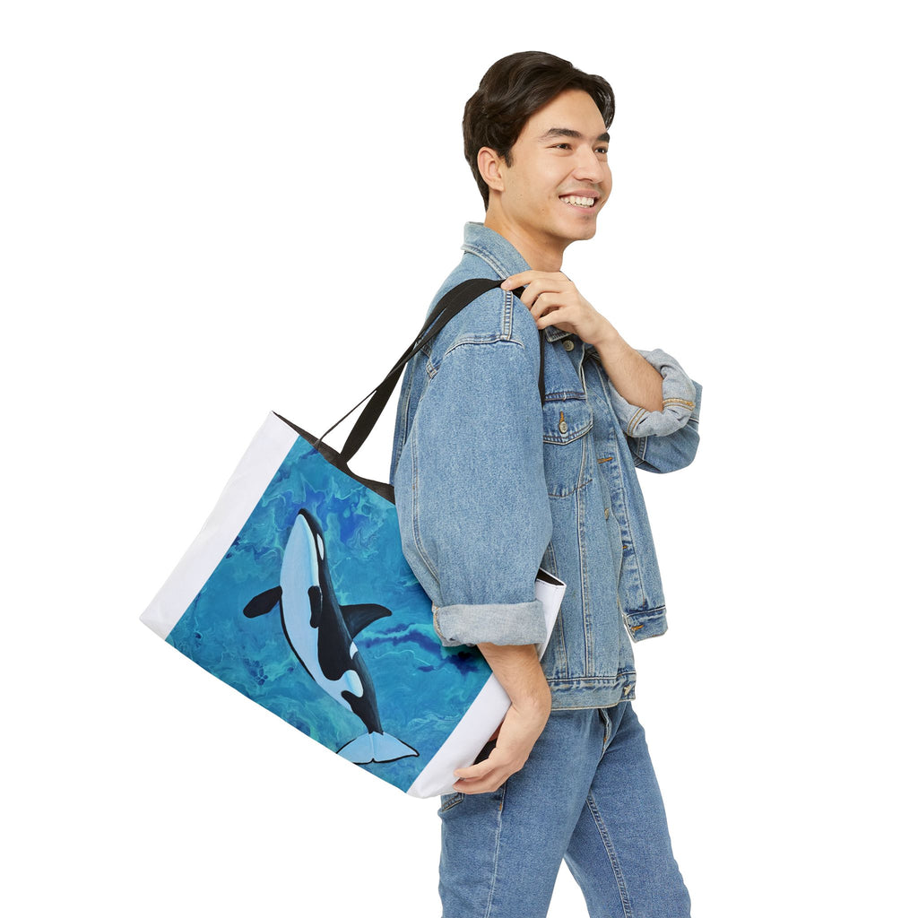 Person holding a tote bag with an orca design on a white background