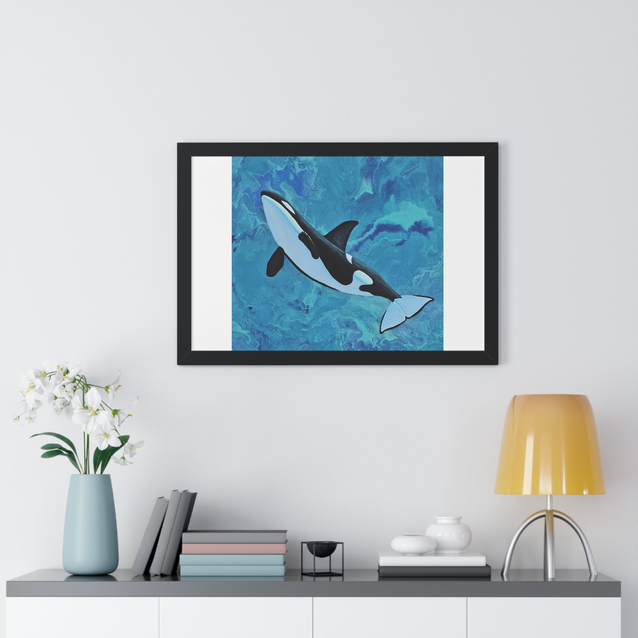 Framed artwork of a whale on a wall above a shelf with decor items.