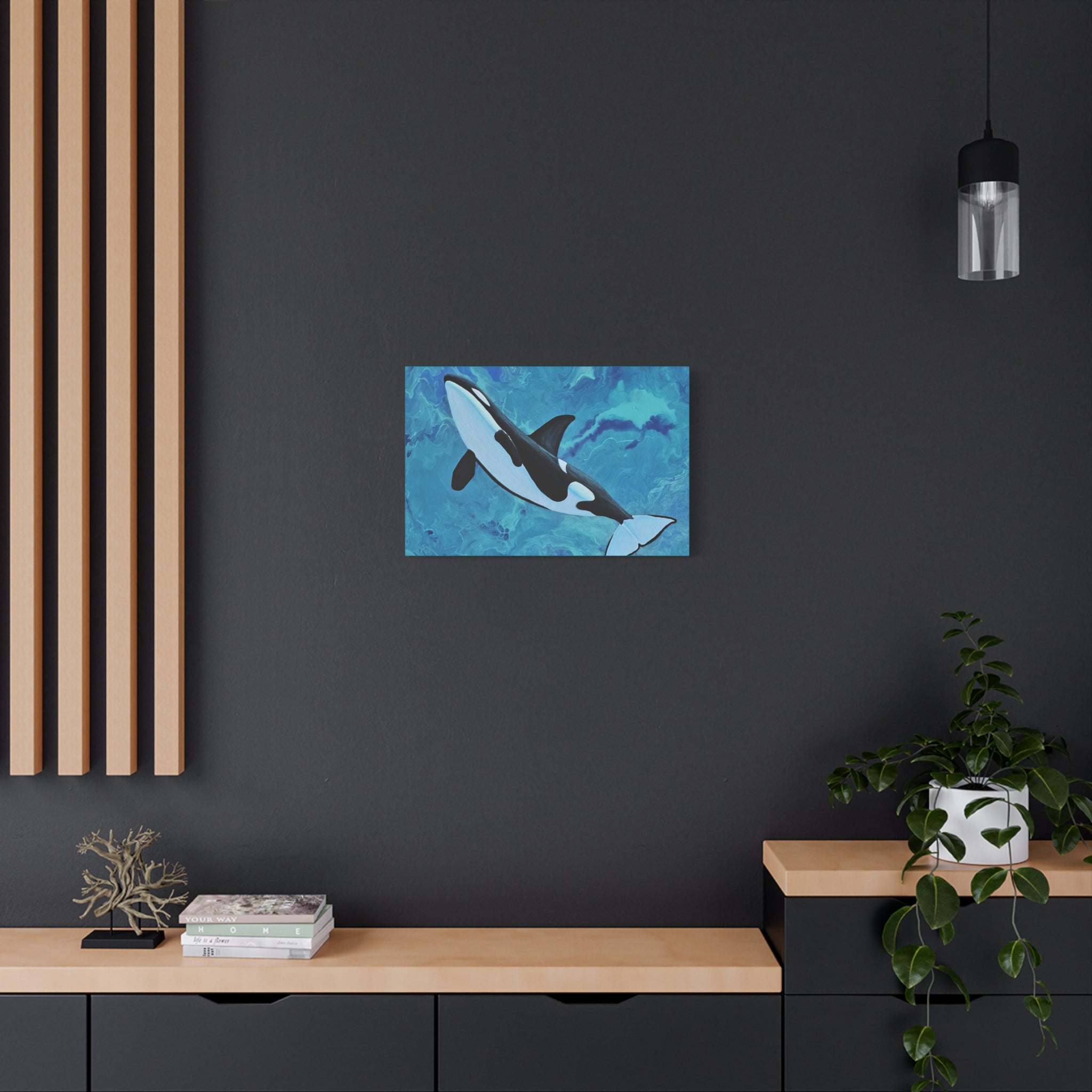 Orca whale painting on a dark wall above a wooden shelf with books and decor.