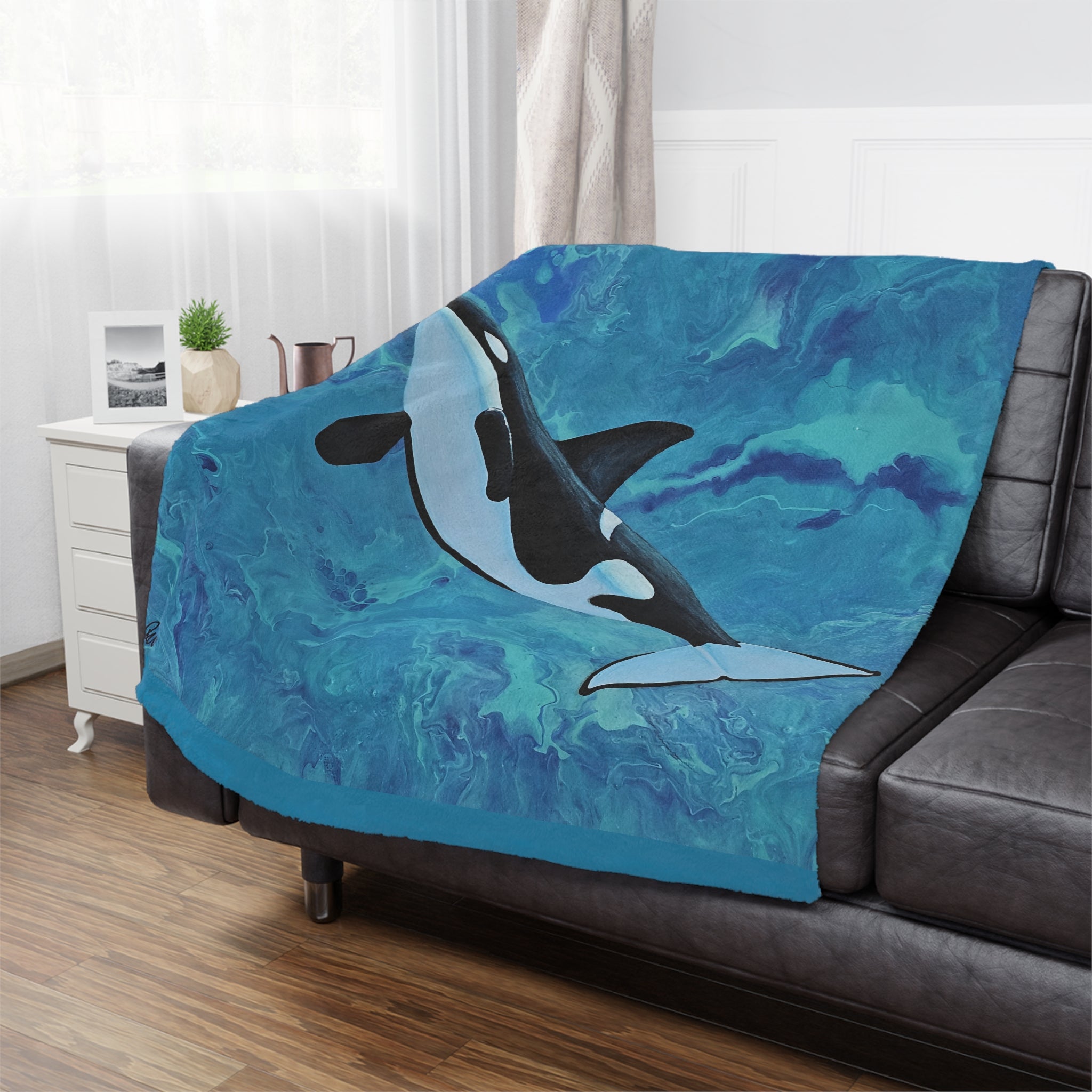 Orca whale design blanket draped over a sofa in a living room setting.