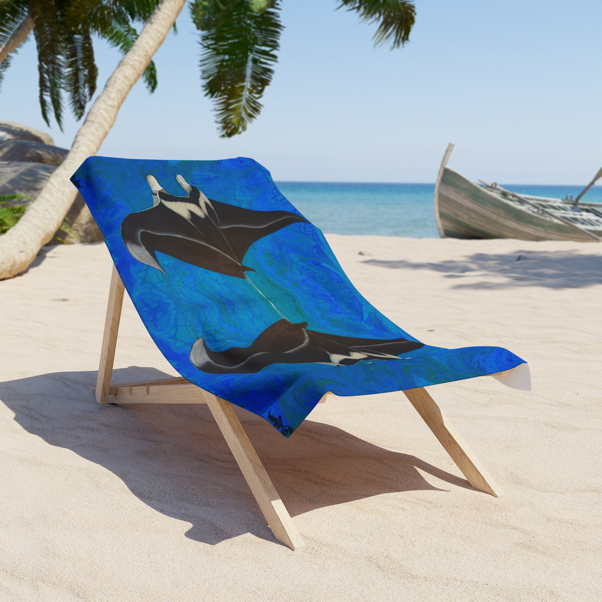 Beach towel/blanket with manta ray design on a wooden chair at a tropical beach.
