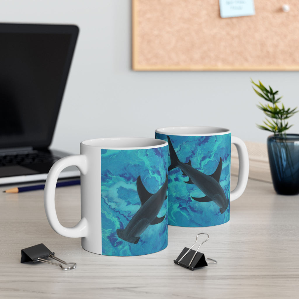 Two mugs with shark design on a desk with office items.
