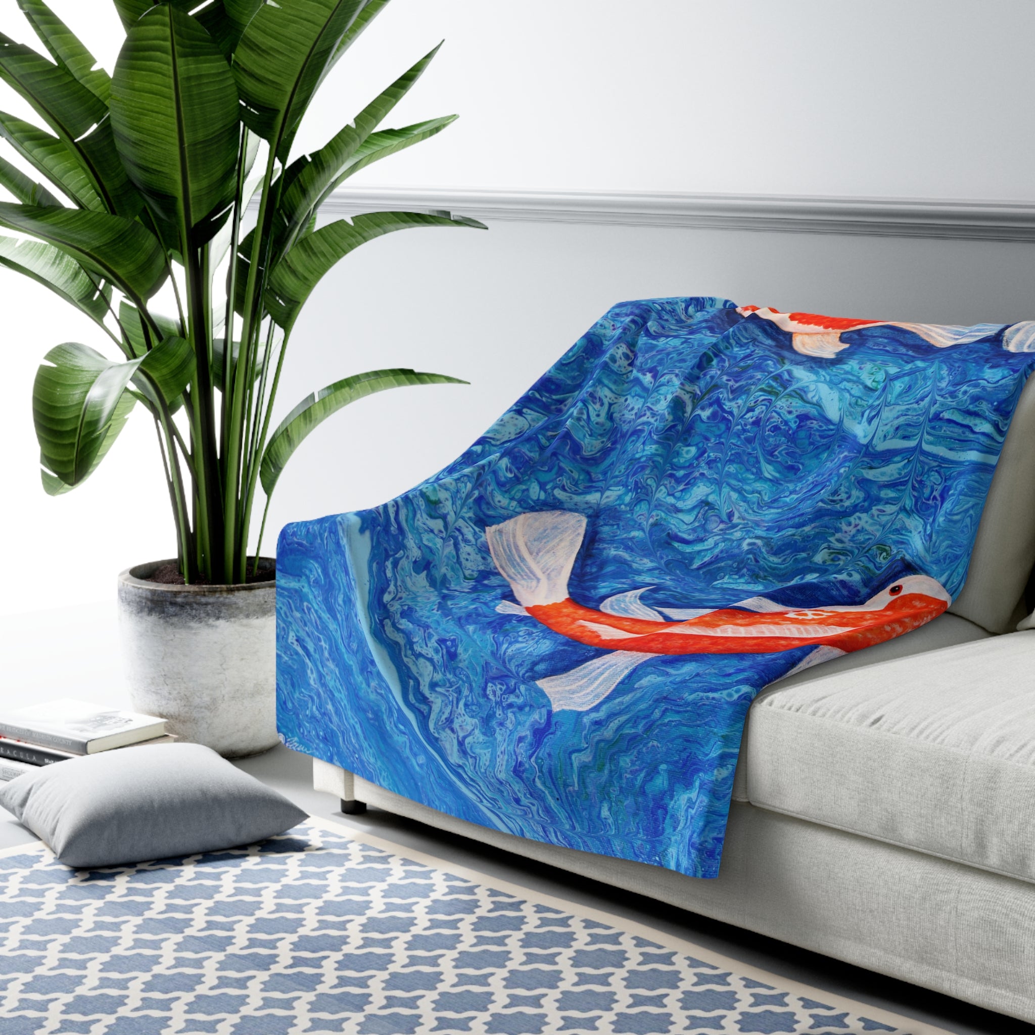 Sofa with a blue and orange fish patterned throw blanket in a living room setting.
