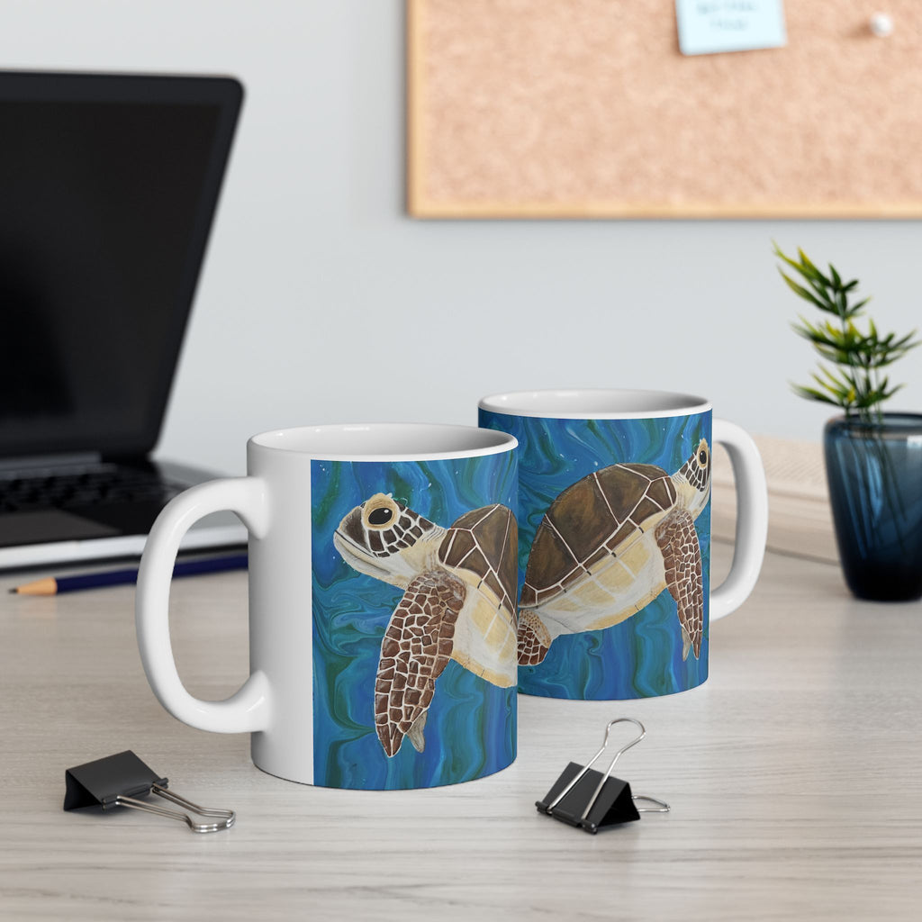 Two mugs with turtle designs on a desk with office supplies.