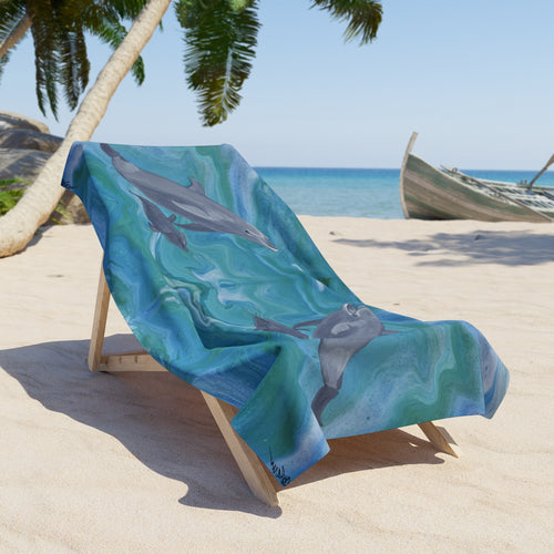 Beach towel/blanket with dolphin design on a wooden chair at a tropical beach.