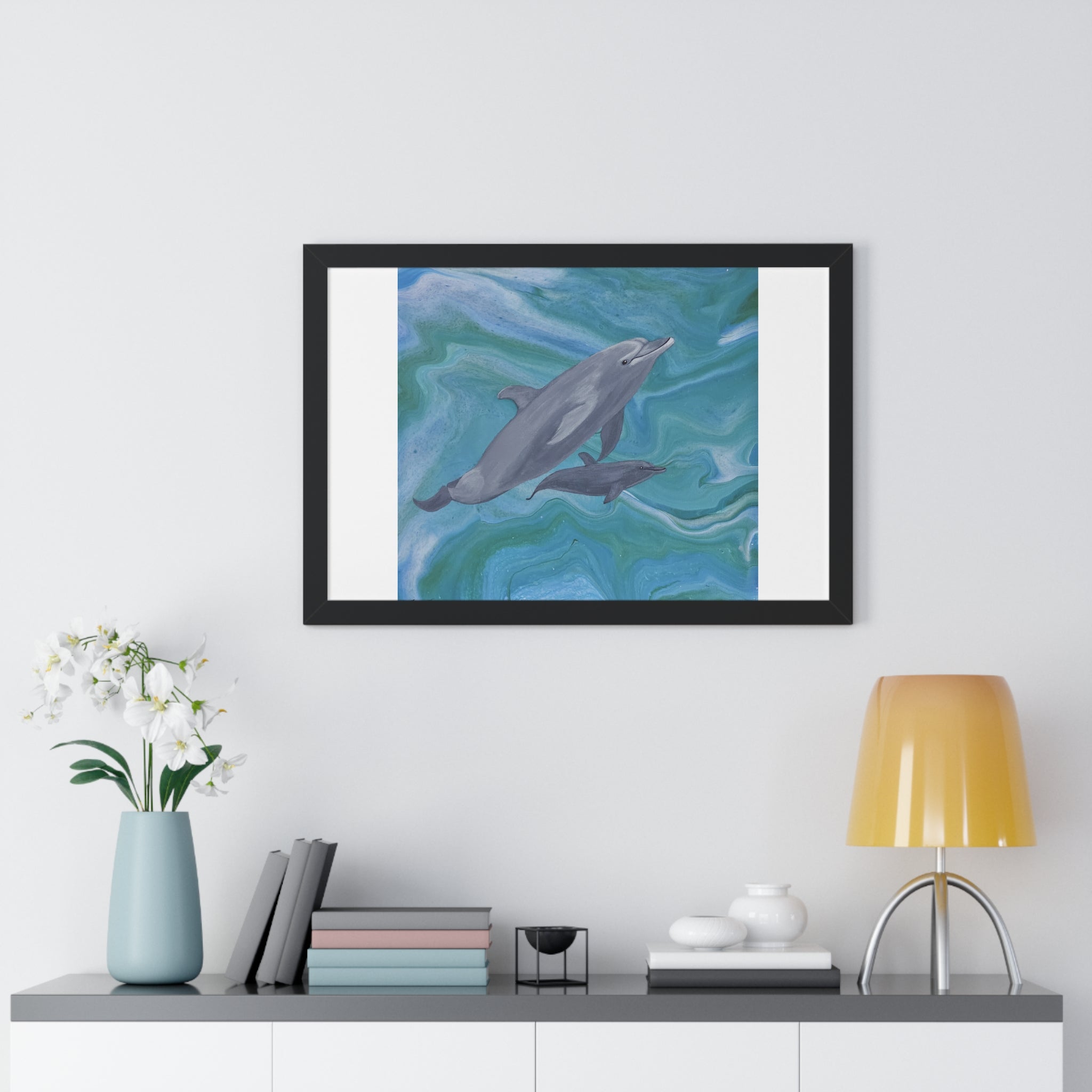 Framed artwork of dolphins on a wall above a shelf with decor items.