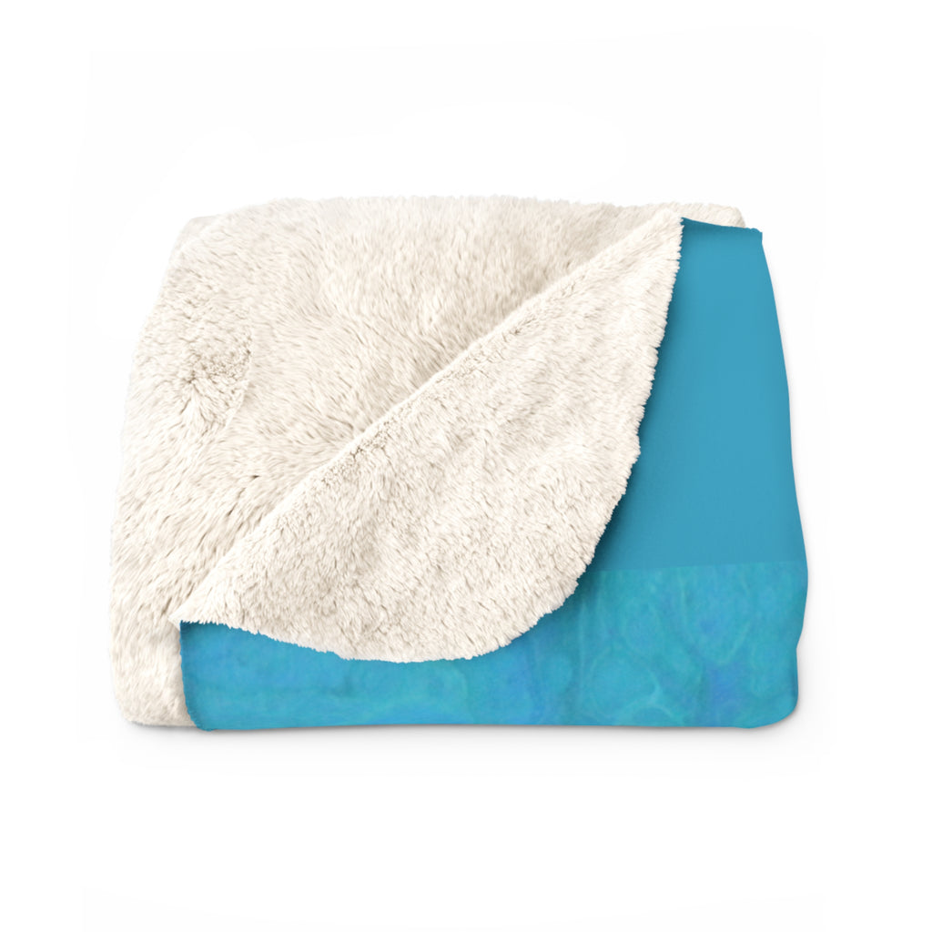 Folded blanket with white sherpa side and blue backside on a white background
